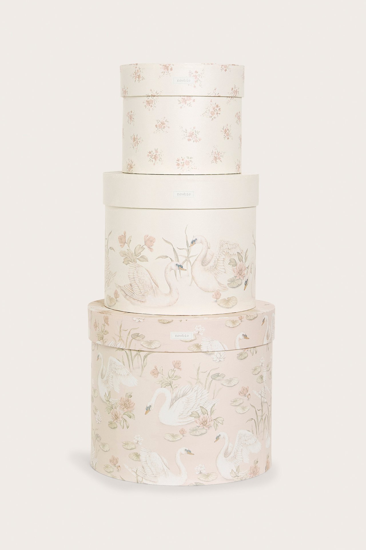 Front view of three stacked round paper storage boxes with floral and swan patterns.