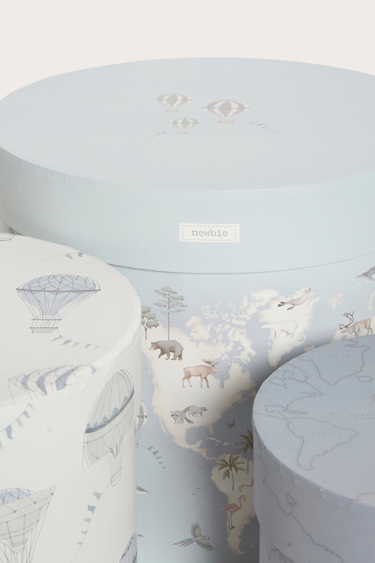 Nahaufnahme: Drei runde hellblaue Papier-Aufbewahrungsboxen, gemustert mit Karten und Heißluftballons.