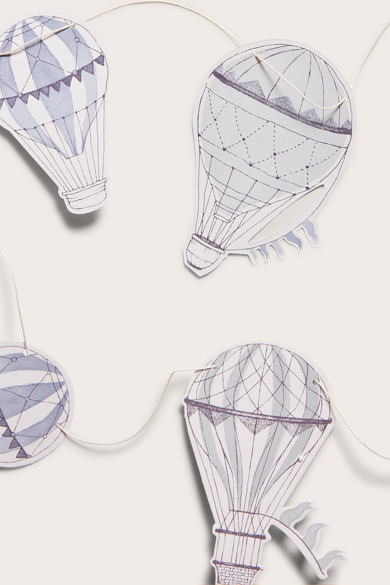 Nahaufnahme einer cremefarbenen Papiergirlande mit gemusterten hellblauen Heißluftballon-Ausschnitten an einer Schnur.