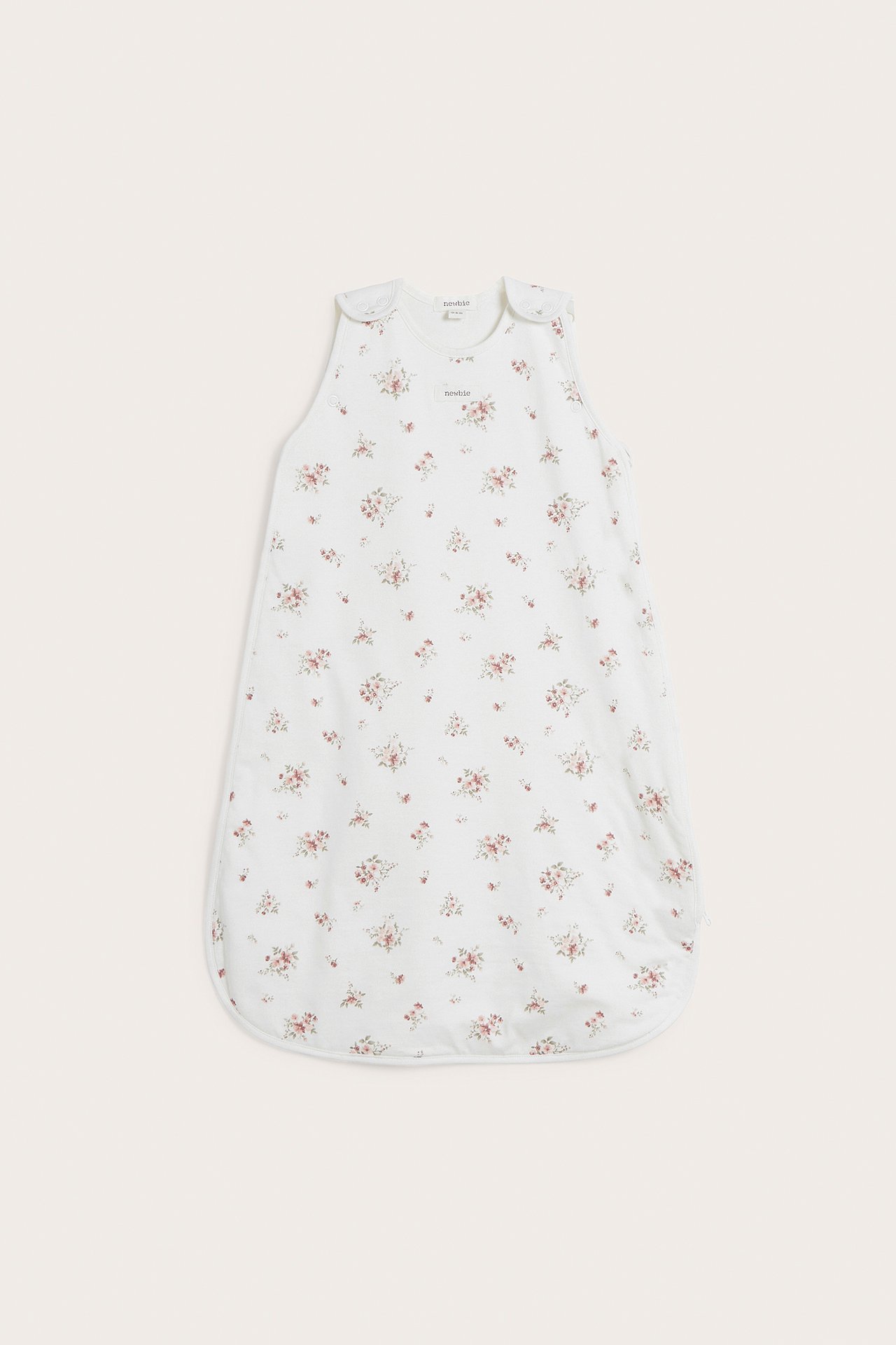 Front view of a white baby sleeping bag with a small pink floral pattern and shoulder snap buttons.