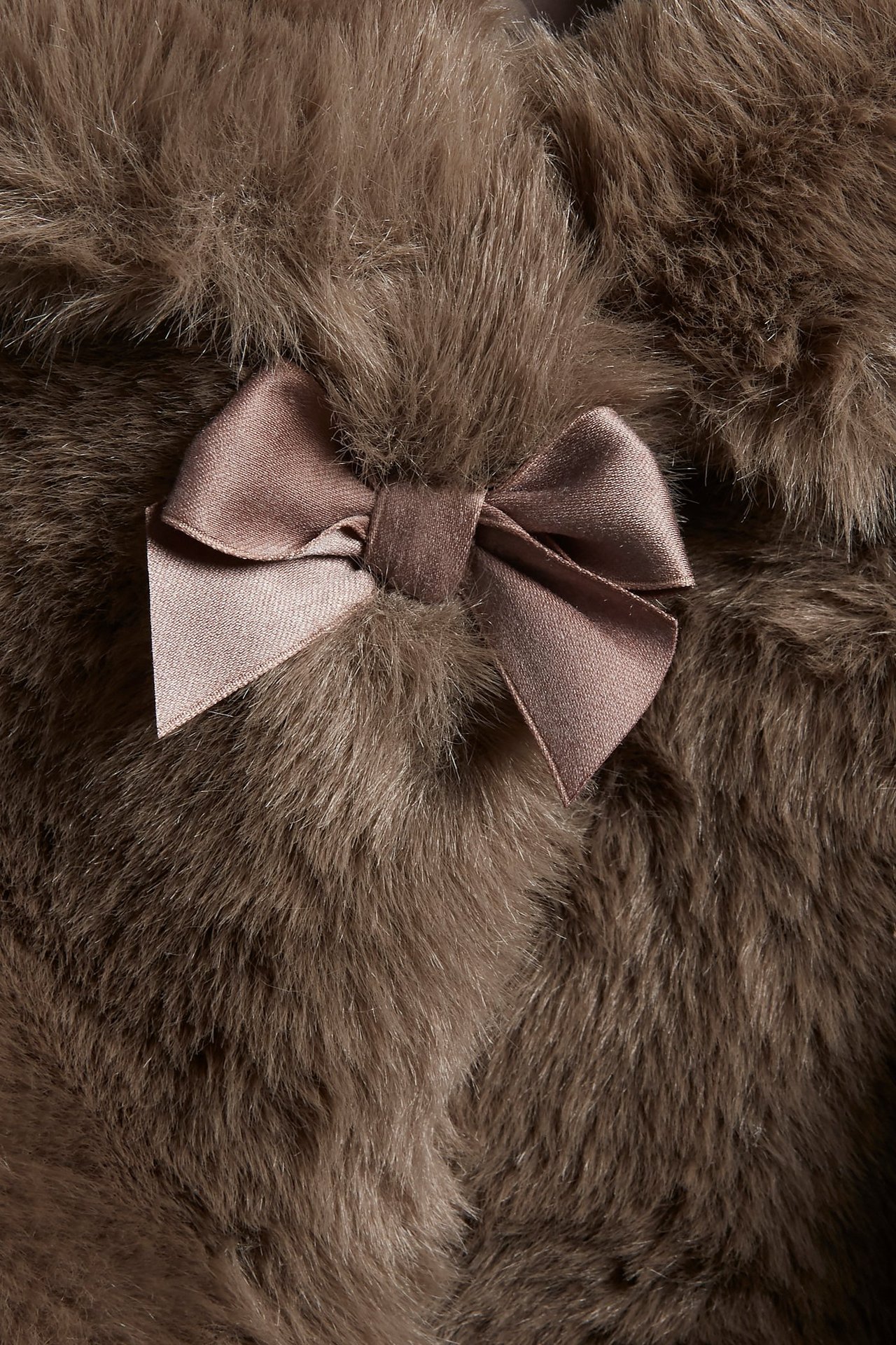 Nahaufnahme einer braunen Kunstpelzjacke mit einer dekorativen Satin-Schleife am Kragen.