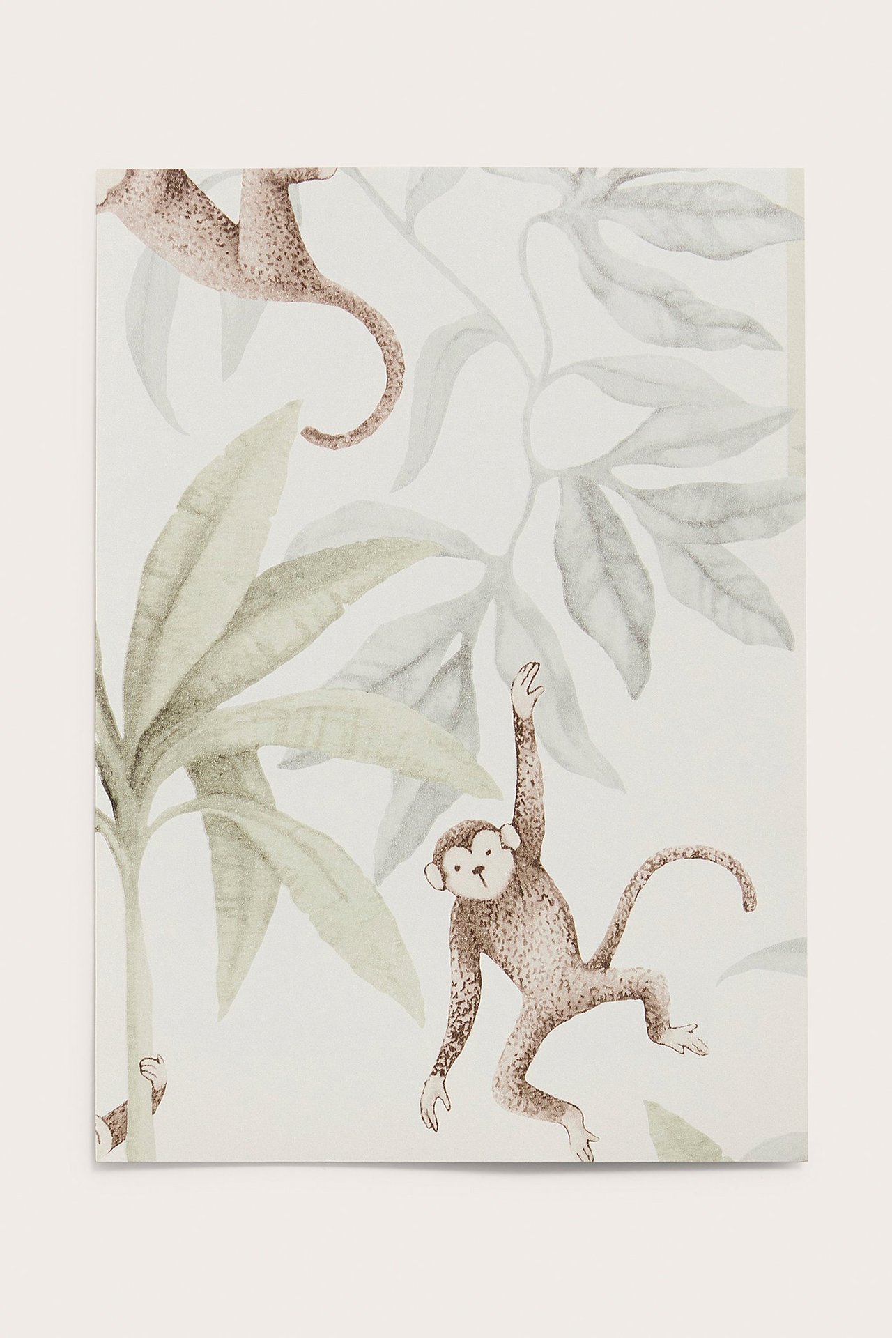 Nahaufnahme einer weißen Tapetenprobe mit braunen Affen und grünem Dschungelblattmuster.