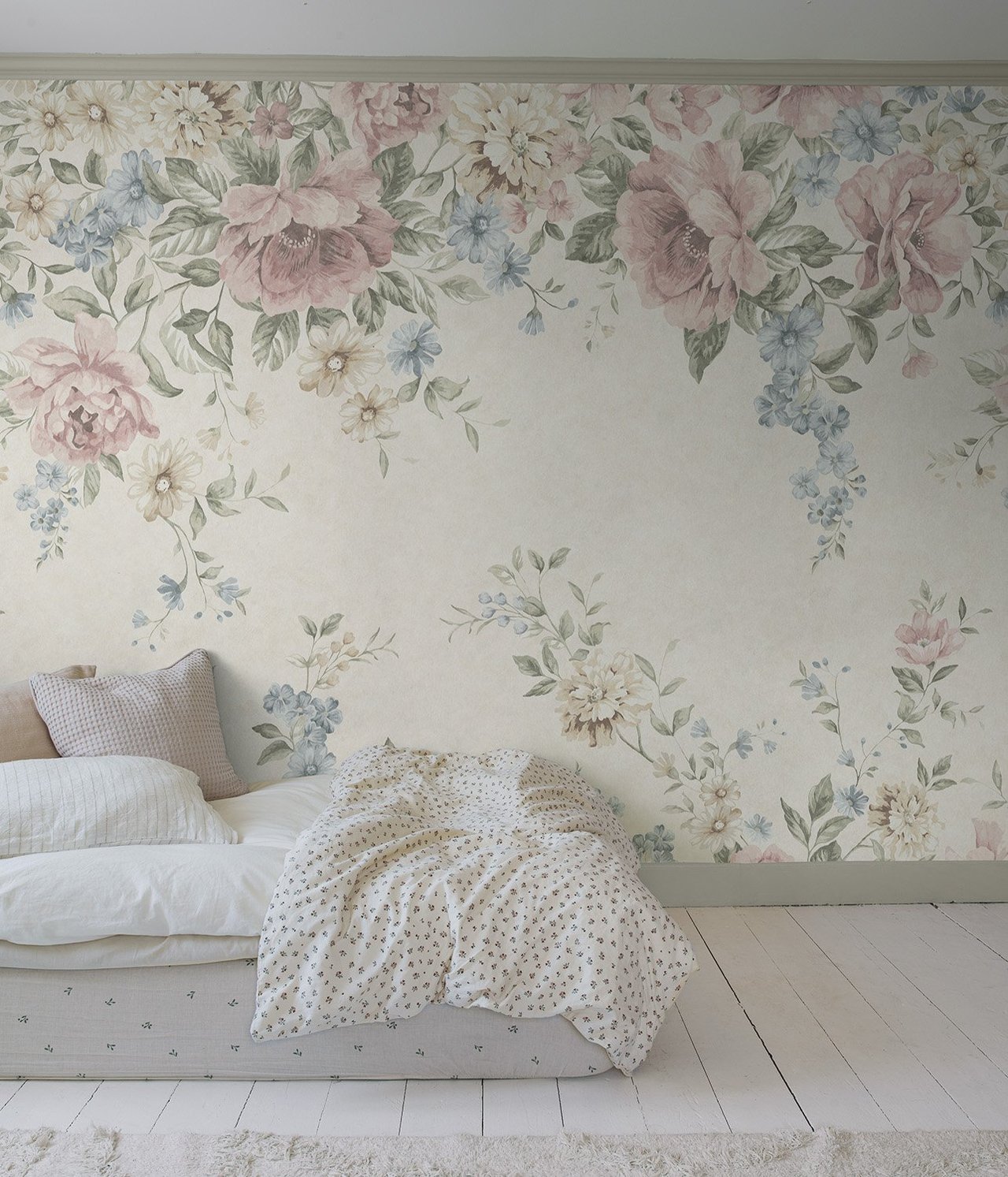 Ganze Wandansicht einer beigen Blumentapeten-Wandmalerei mit rosa und blauen Blumen, über einem Bett mit weißer Bettwäsche.