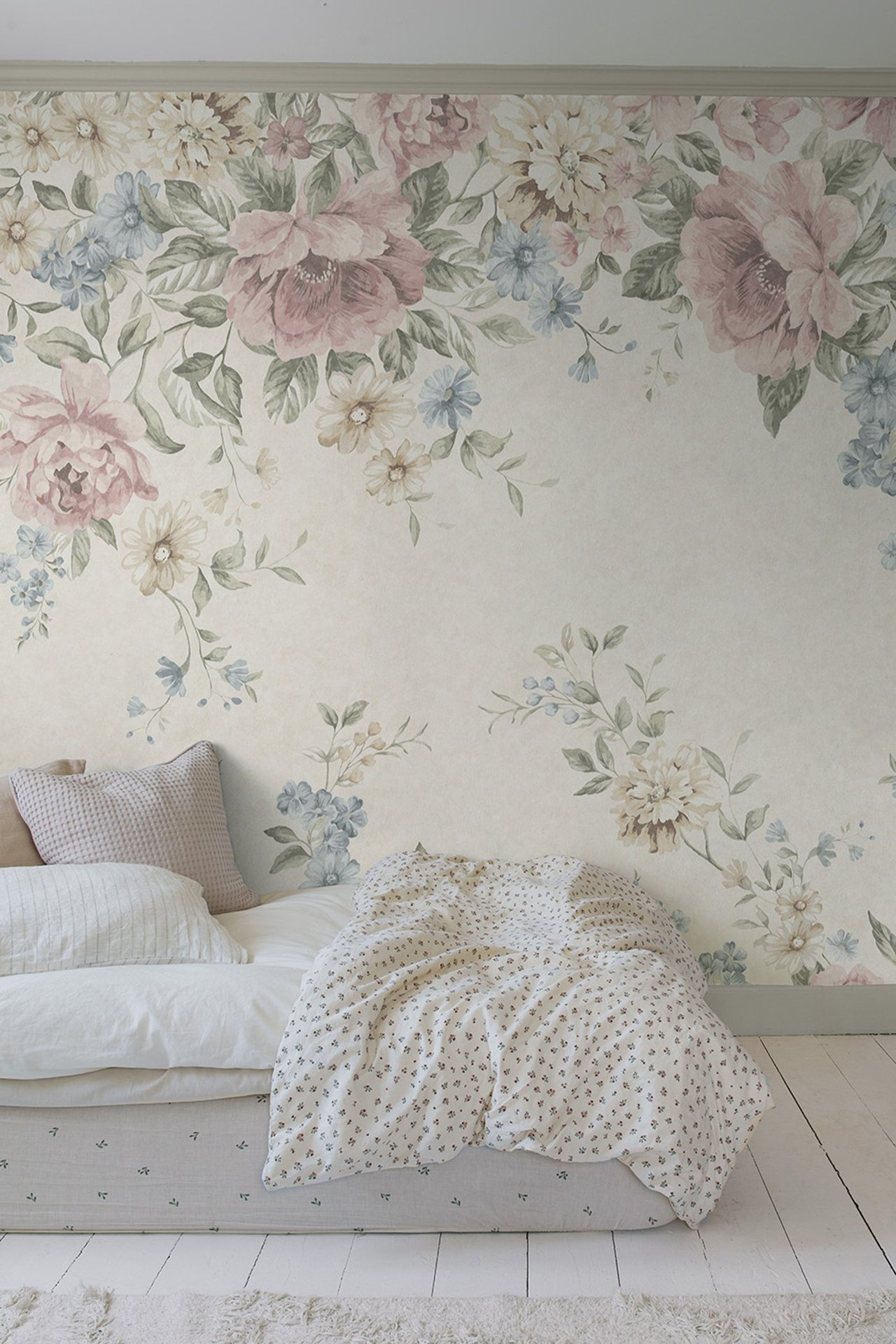Front view: Beige floral wallpaper mural with pink and blue flowers, above a bed with patterned bedding.
