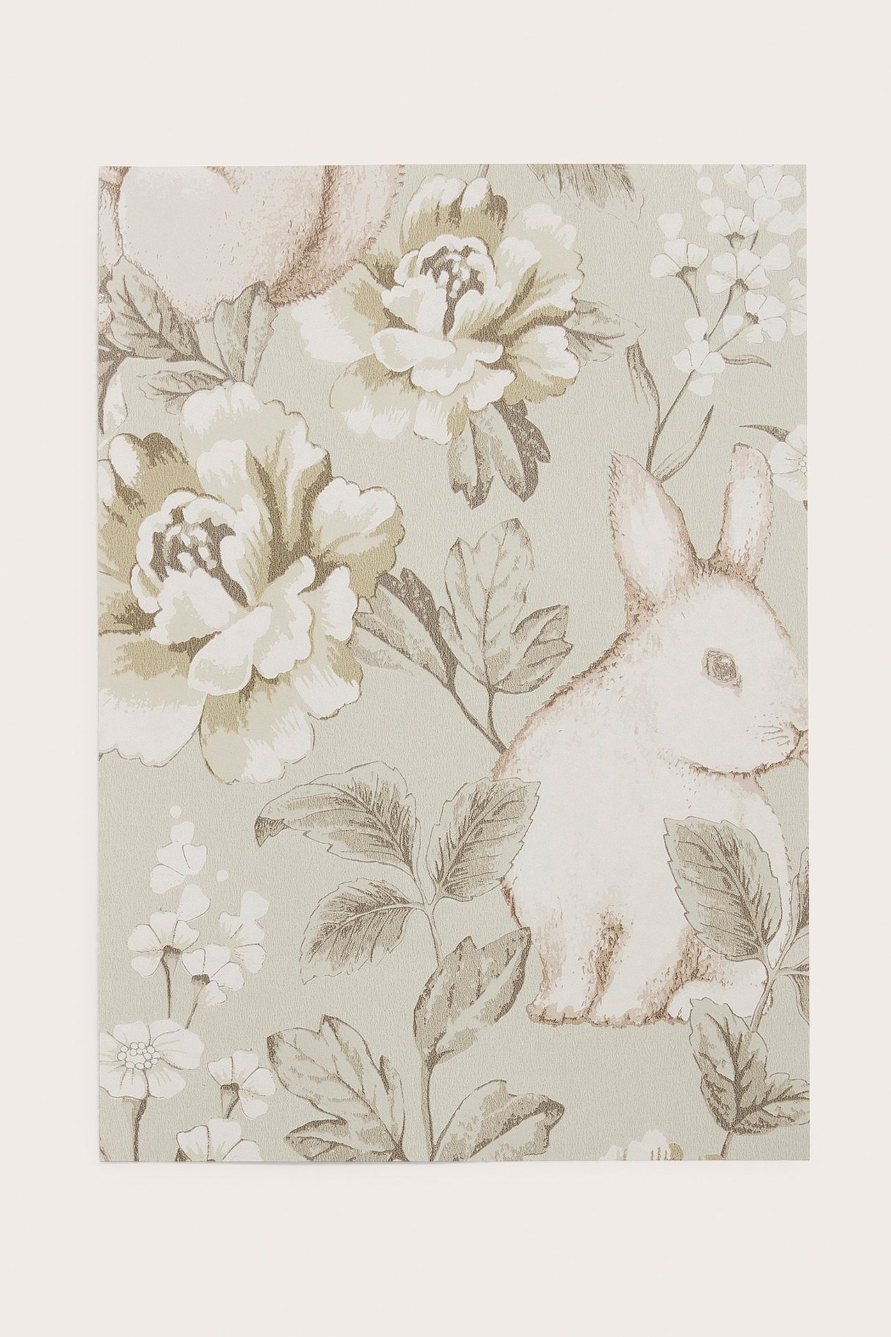 Nahaufnahme einer beigen gemusterten Vliestapetenprobe mit Hasen und Blumen.