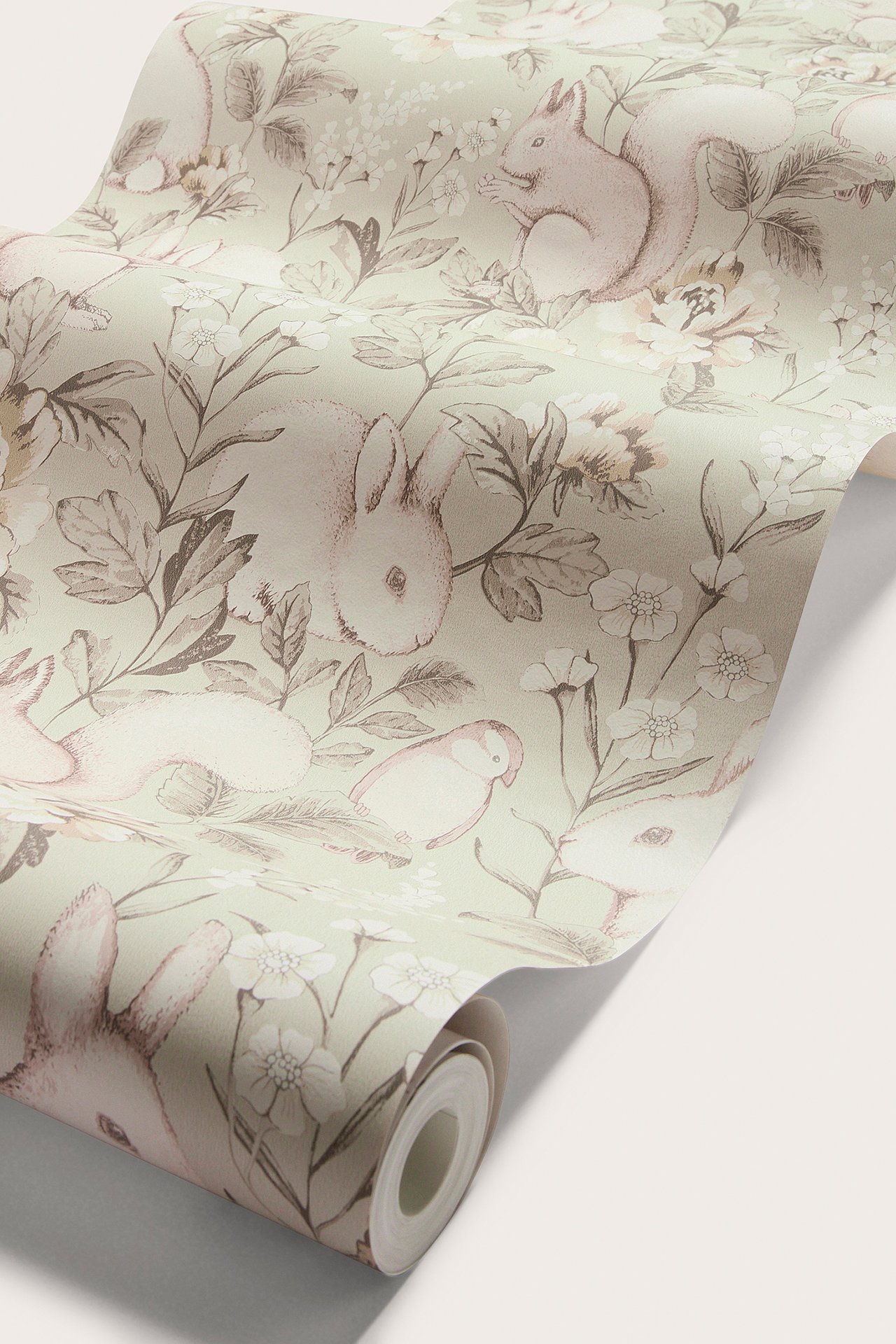 Close-up of a beige patterned wallpaper roll with a forest motif of animals and flowers.