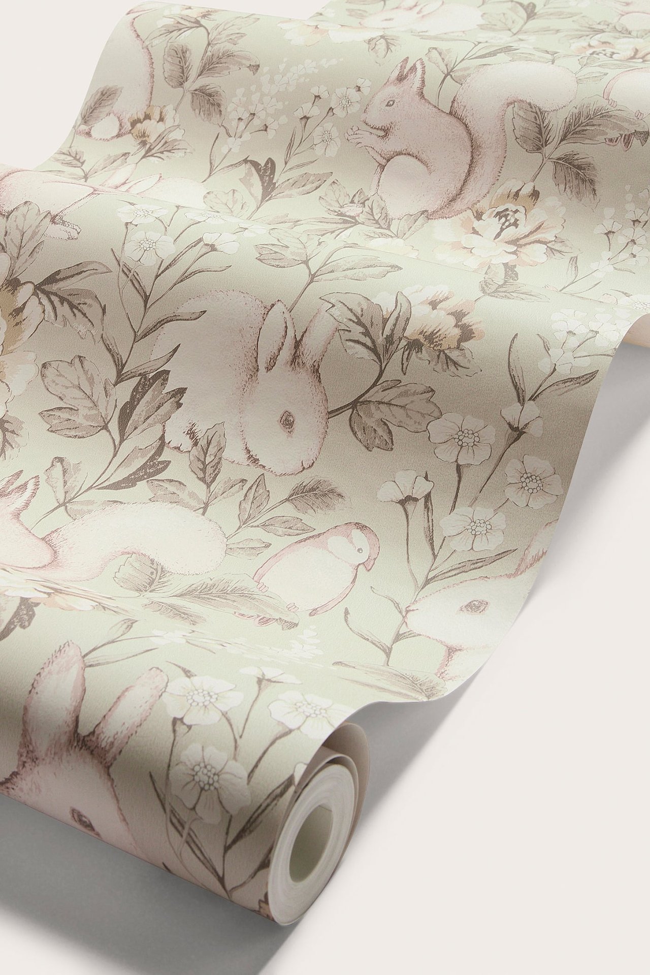 Nahaufnahme einer beigen gemusterten Tapetenrolle mit Waldmotiv aus Tieren und Blumen.