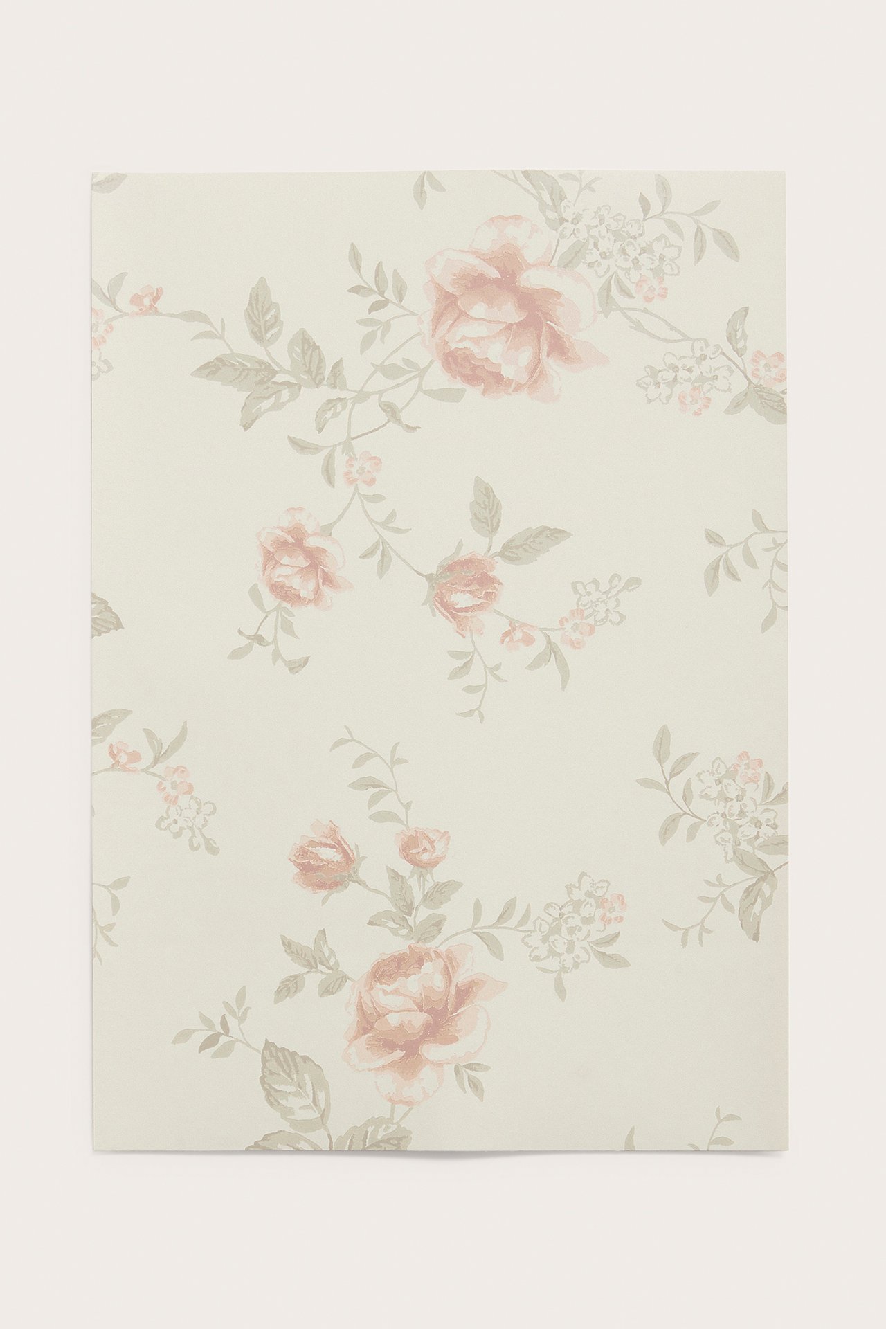 Front view of a beige wallpaper sample with a floral rose garden pattern in pink and green.