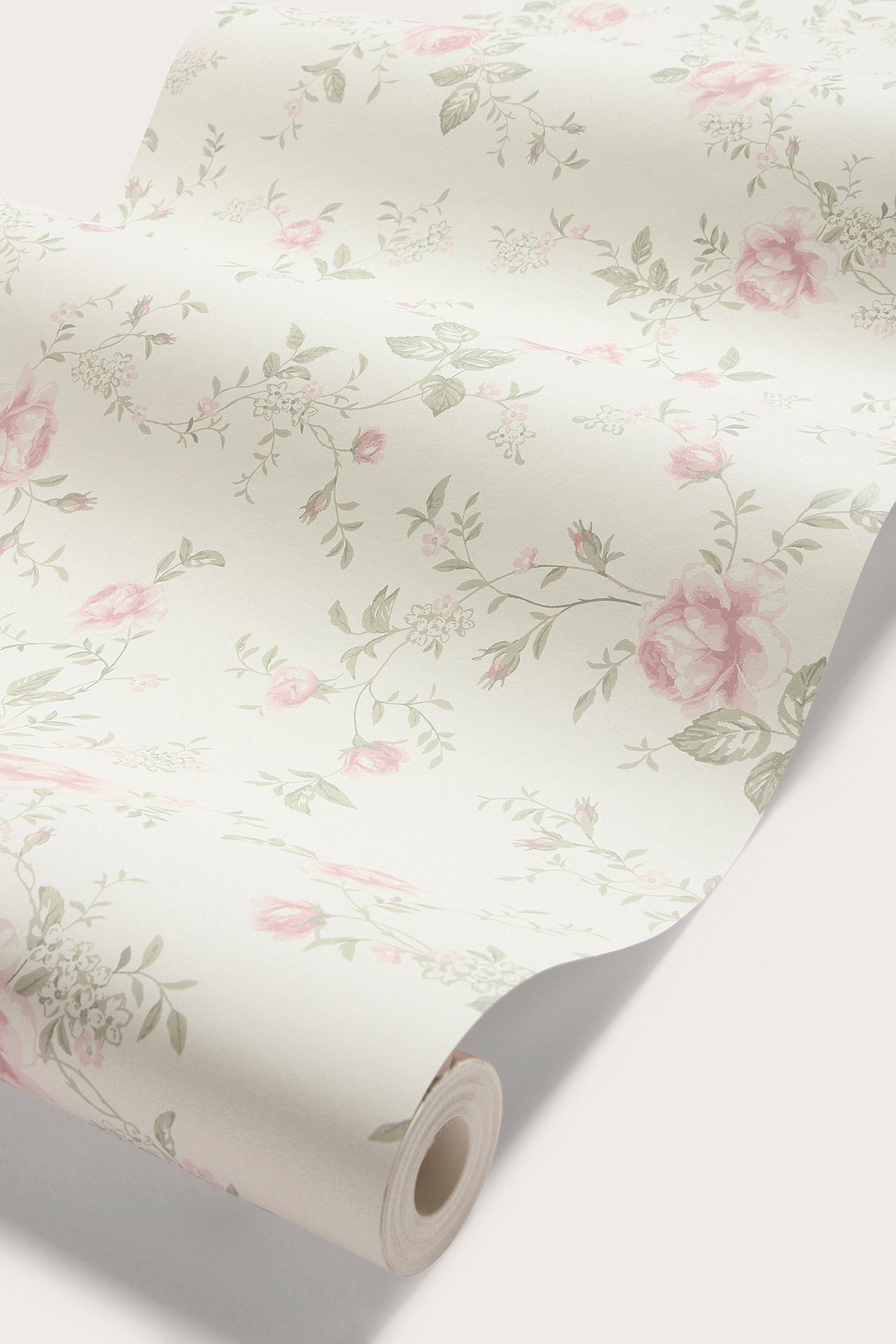 Angled view of a warm white wallpaper roll with light pink roses and green leaves floral pattern.