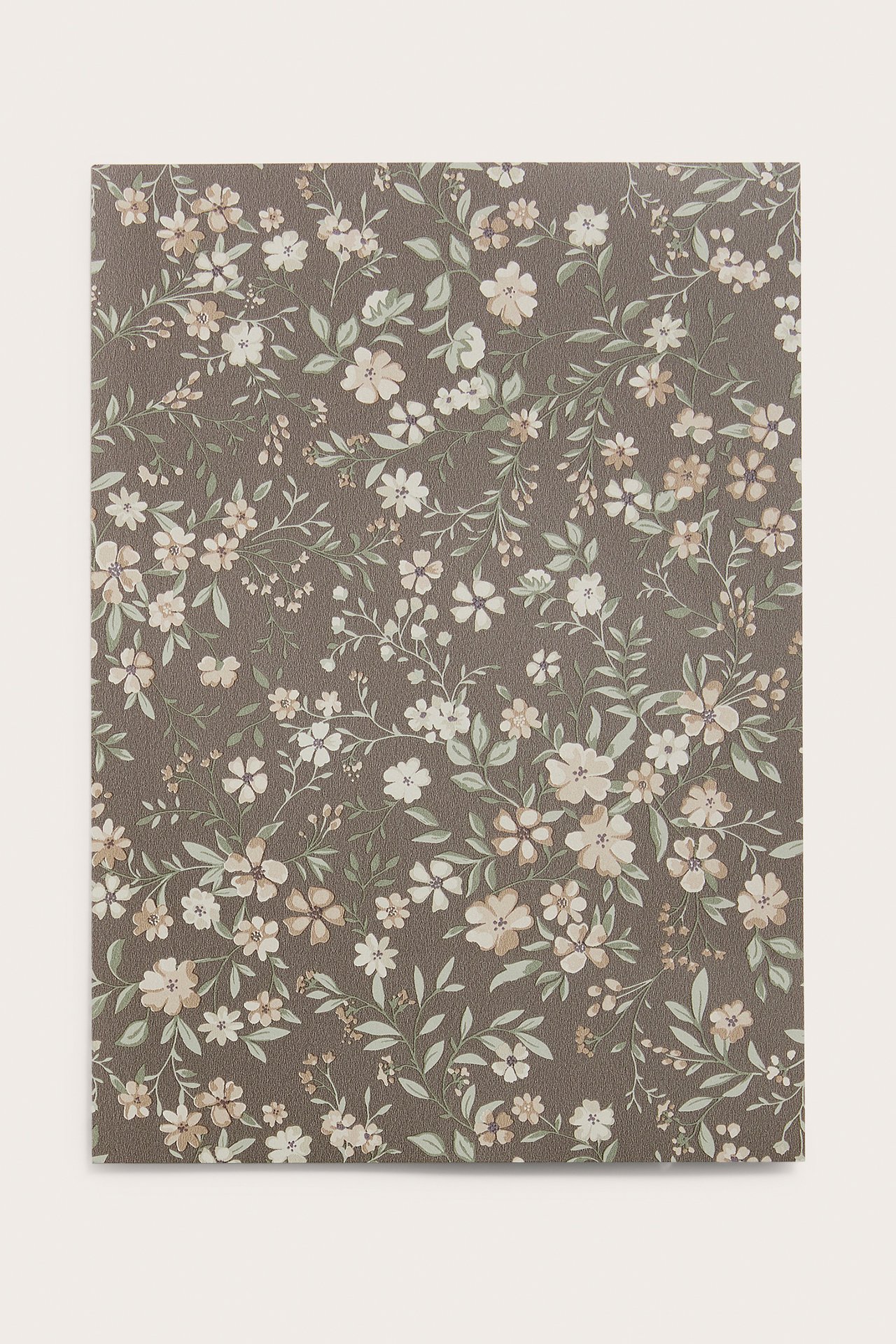 Front view of a brown wallpaper sample with a small floral pattern in cream, beige, and light green.