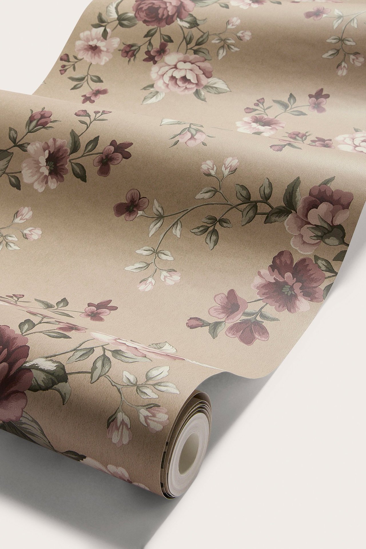 Close-up of a rolled light brown non-woven wallpaper with a floral pattern of pink and purple flowers.