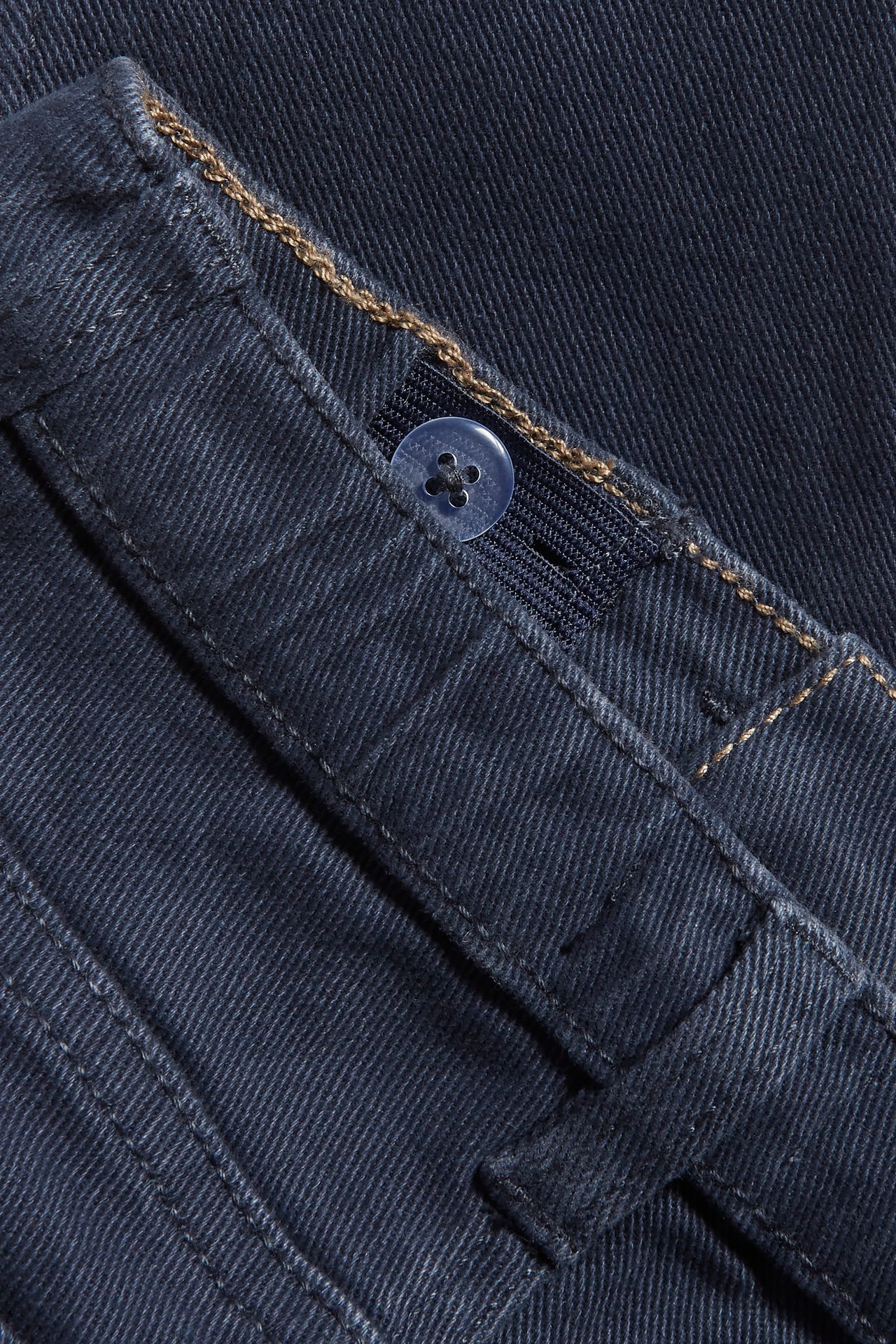Nahaufnahme von dunkelblauen gewebten Twill-Hosen mit verstellbarem Gummizug, Knopf und Gürtelschlaufen.