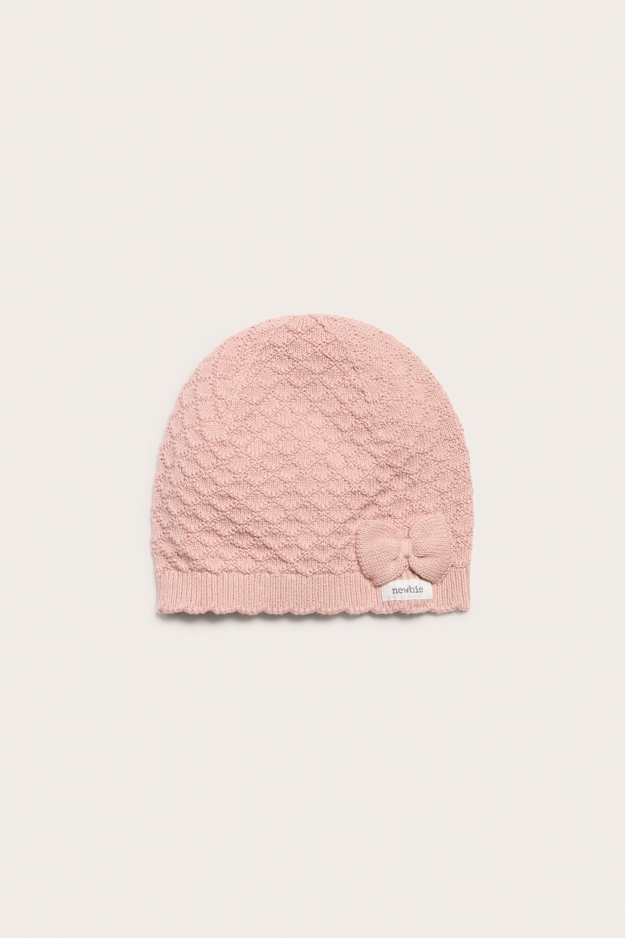Vorderansicht: Rosa gemusterte Baumwoll-Strickmütze für Baby/Kind mit kleiner Schleife und geripptem Saum.