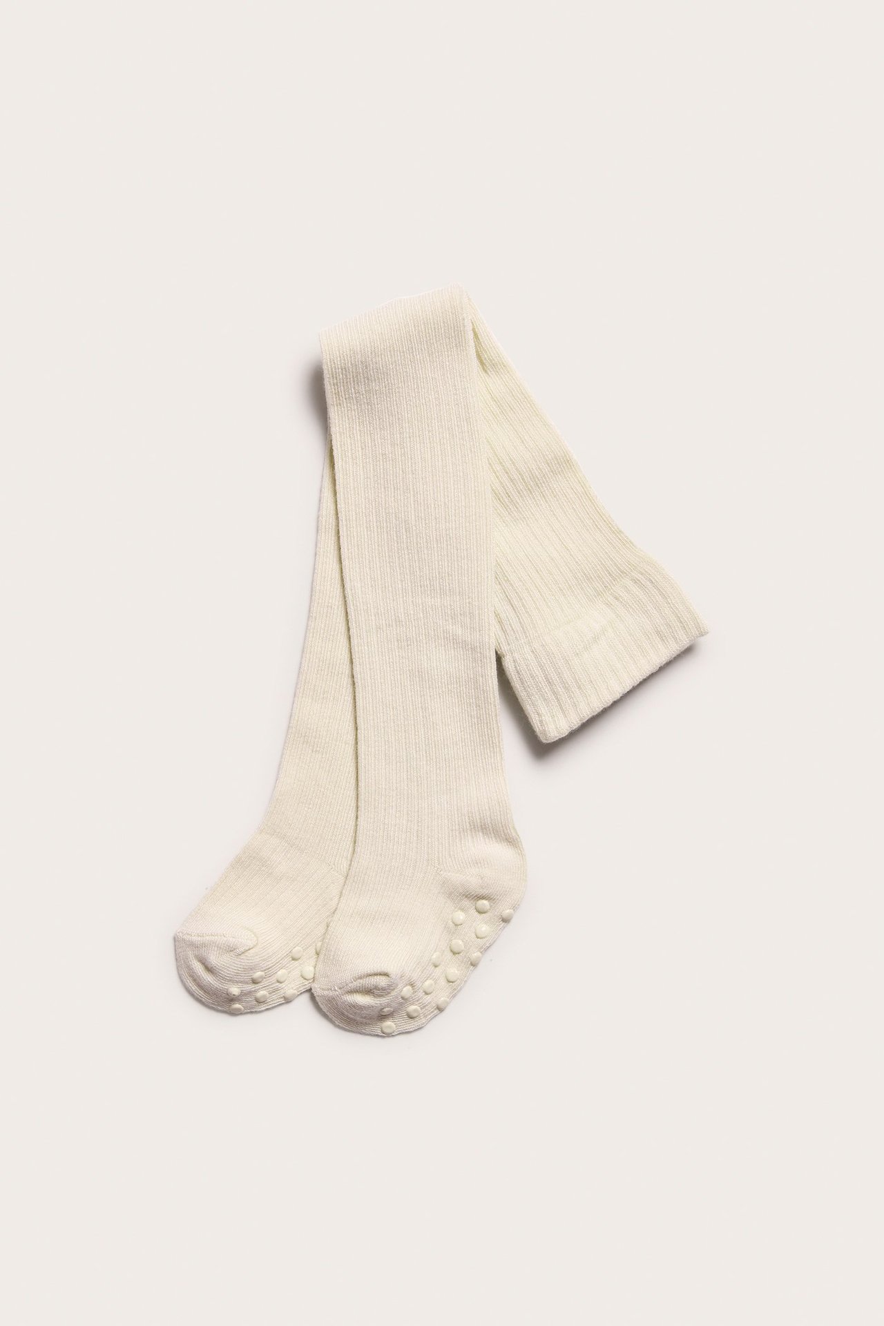 Top-down view of light beige ribbed baby tights with anti-slip soles.