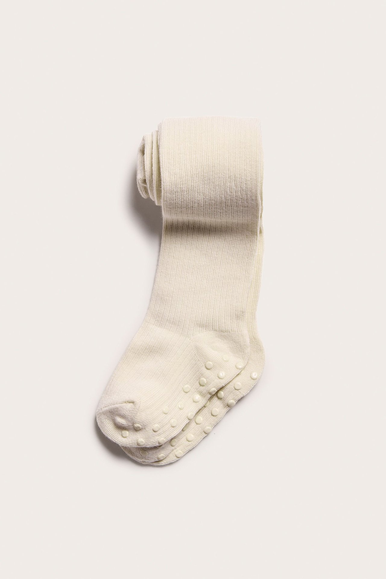 Draufsicht auf gefaltete hellbeige gerippte Baumwollstrumpfhosen mit Antirutsch-Sohlen.