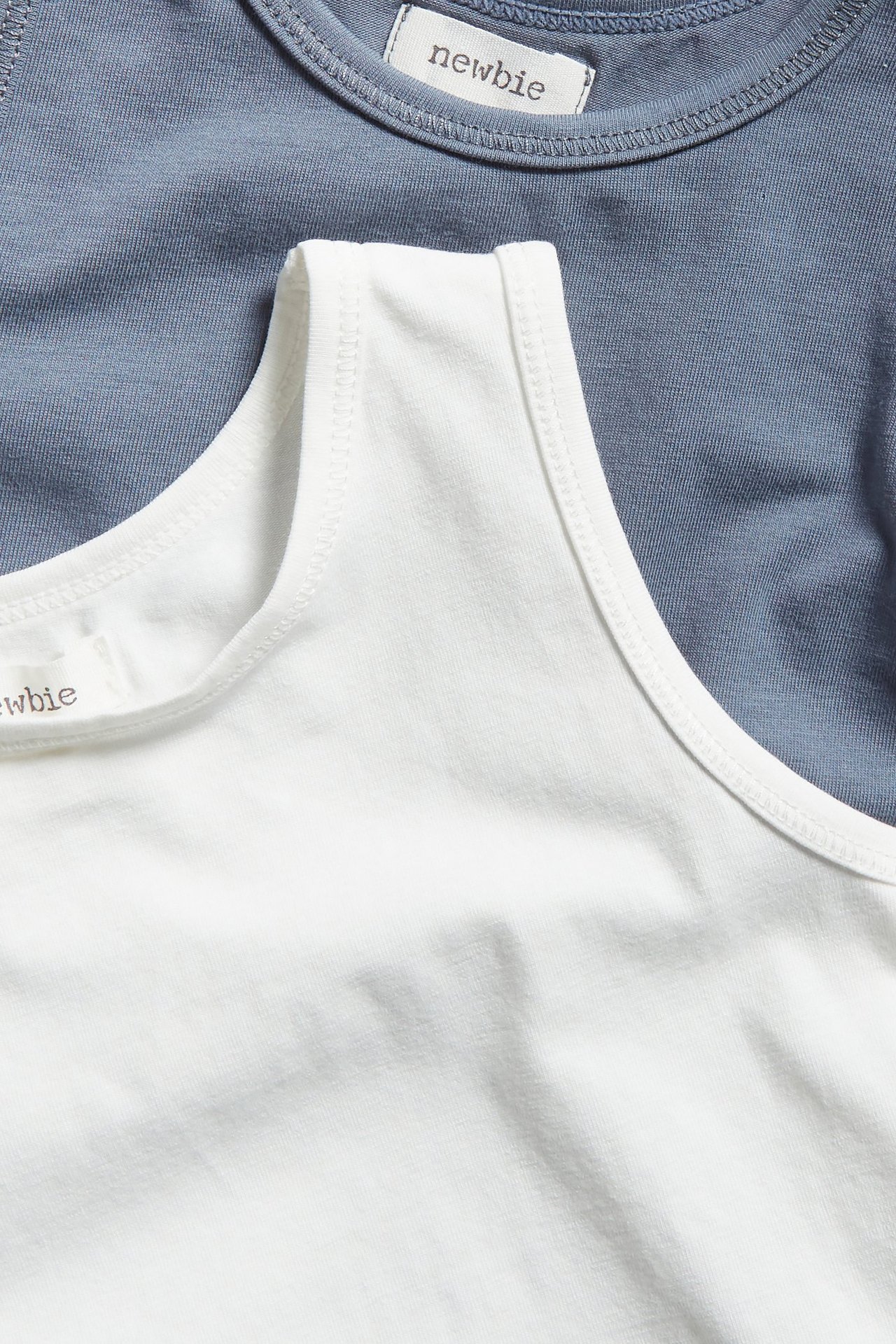 Nahaufnahme eines weißen Baumwoll-Unterhemds mit einem blauen Baumwoll-Unterhemd darunter.