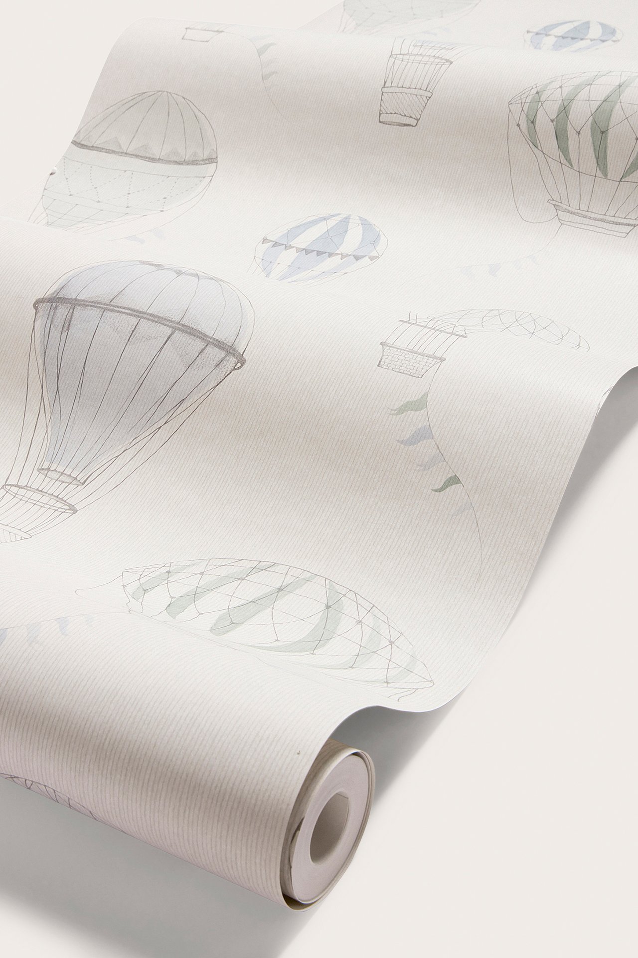Close-up of a light grayish-beige wallpaper roll with blue, green, and gray hot air balloon pattern.