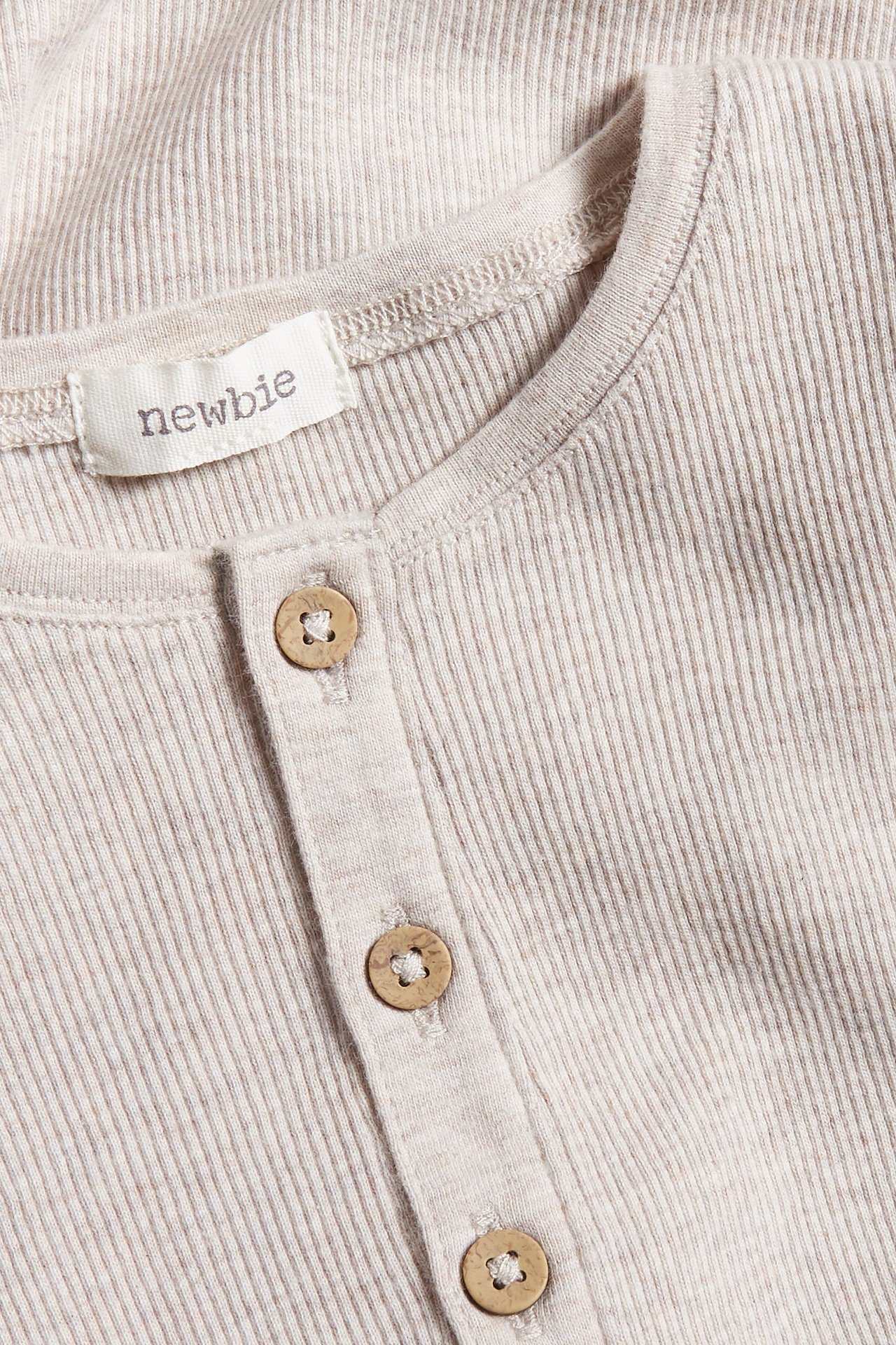 Close-up of a beige melange ribbed long-sleeved baby bodysuit with wooden buttons on the placket.