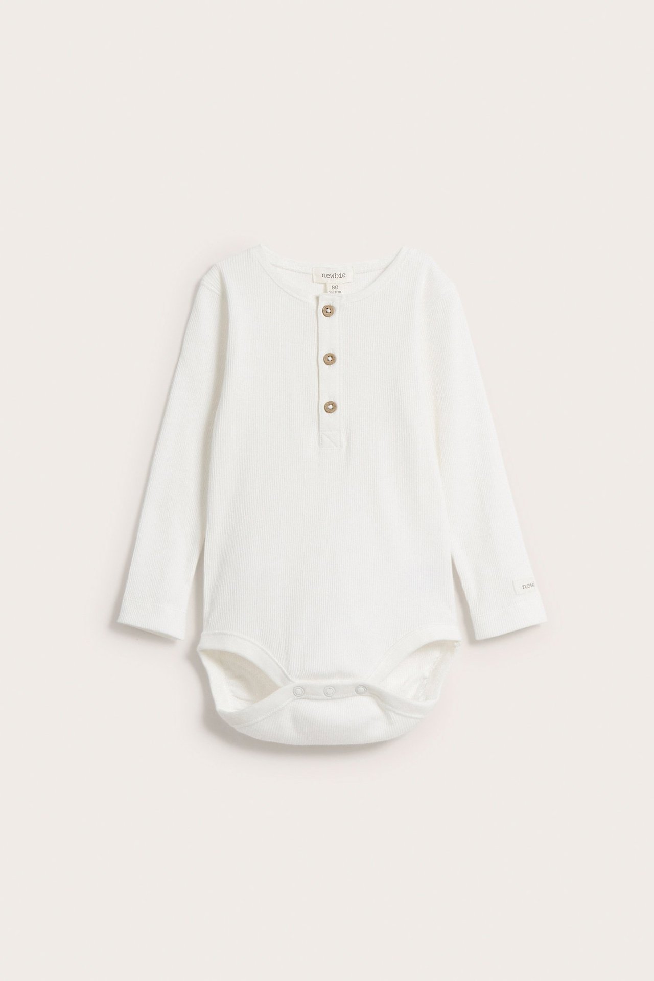 Front view of a white ribbed long-sleeved baby bodysuit with wooden buttons and crotch snap fasteners.