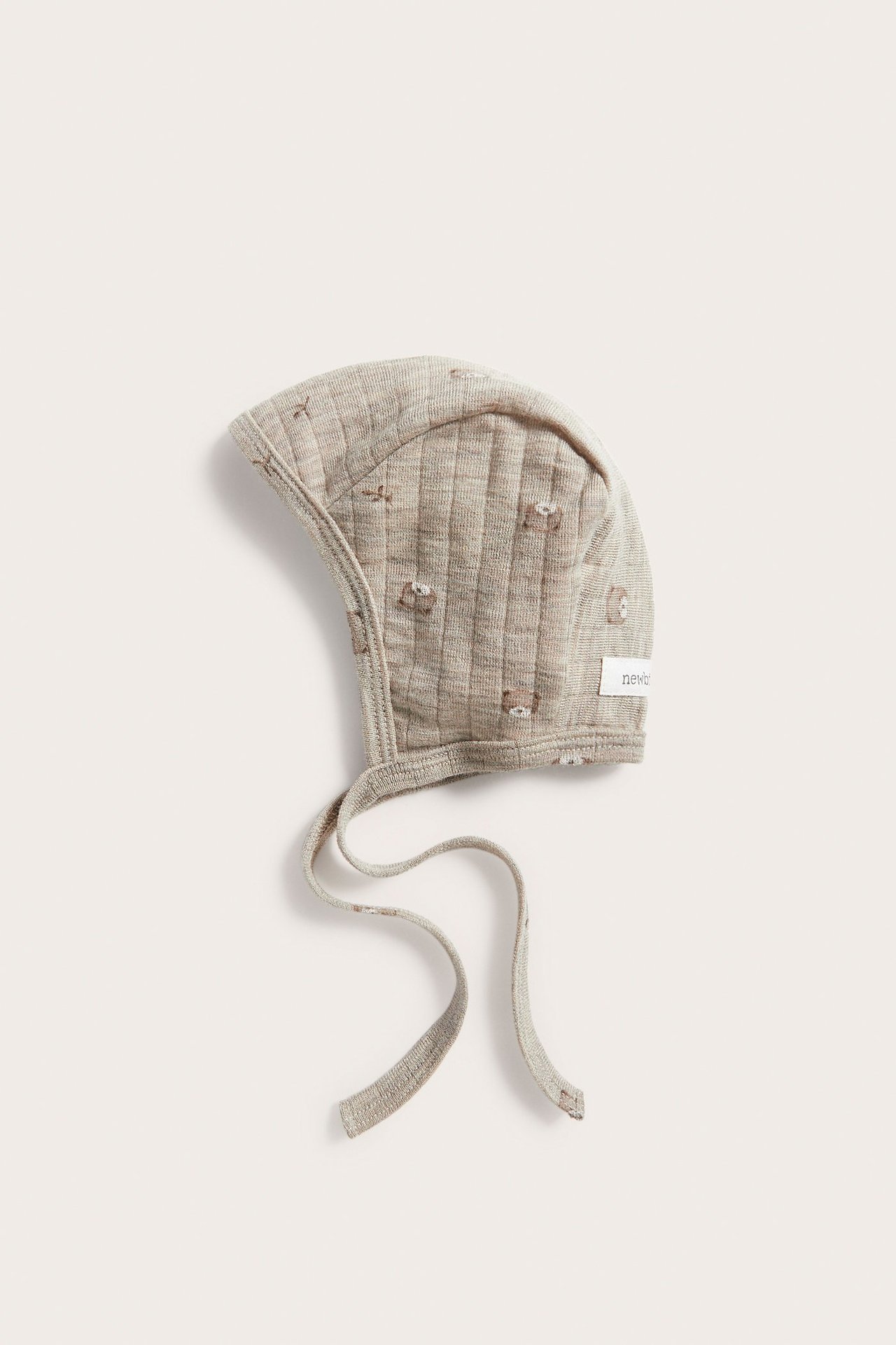 Top view: Beige melange ribbed baby wool bonnet with teddy bear pattern and tie-strings.