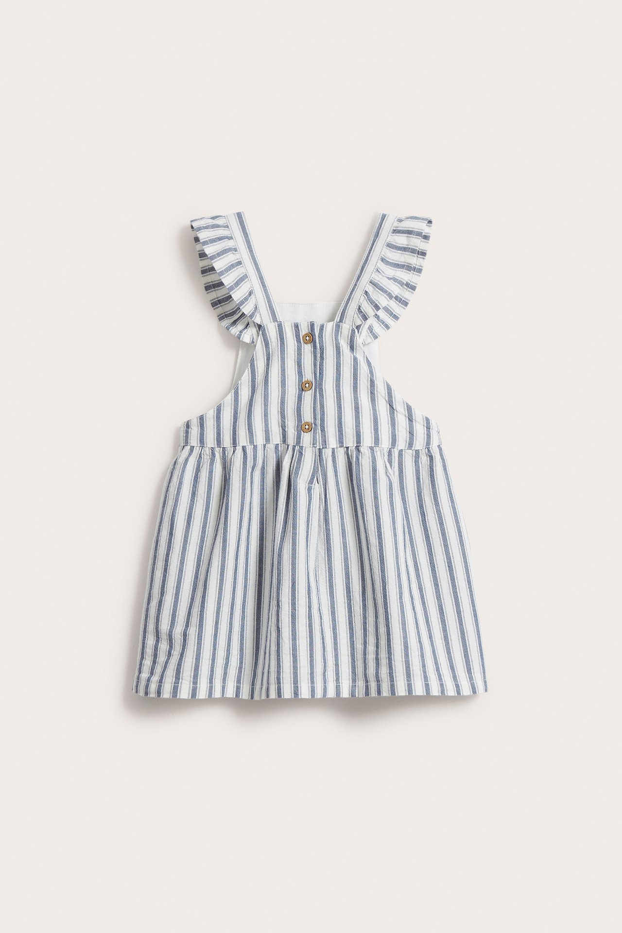 Vorderansicht eines blau-weiß gestreiften Baby-Latzkleides mit Rüschen-Trägern und Knöpfen vorne.
