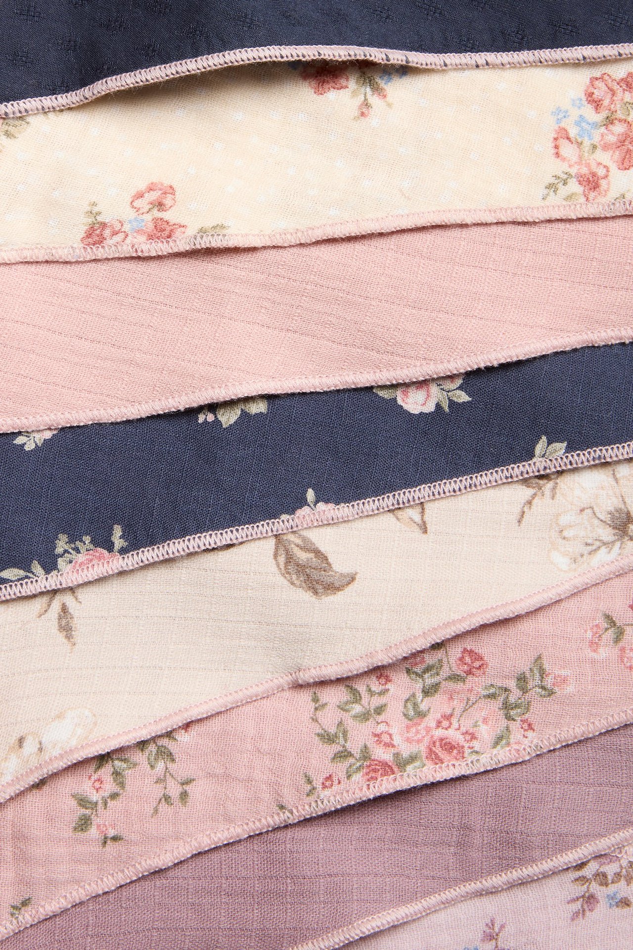 Close-up of pennant flags made from patterned and solid cotton fabrics in pink, beige, blue, and purple.