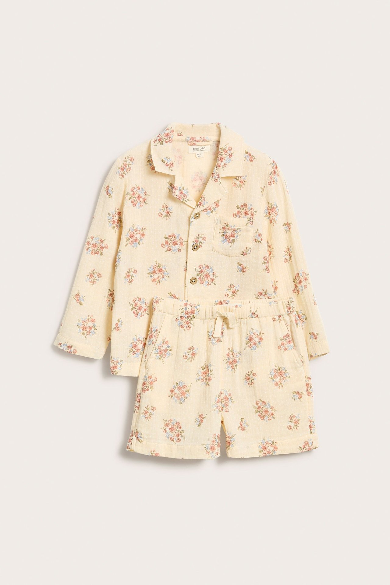 Front view of a light yellow floral woven cotton pajama set with a long-sleeved shirt and shorts.