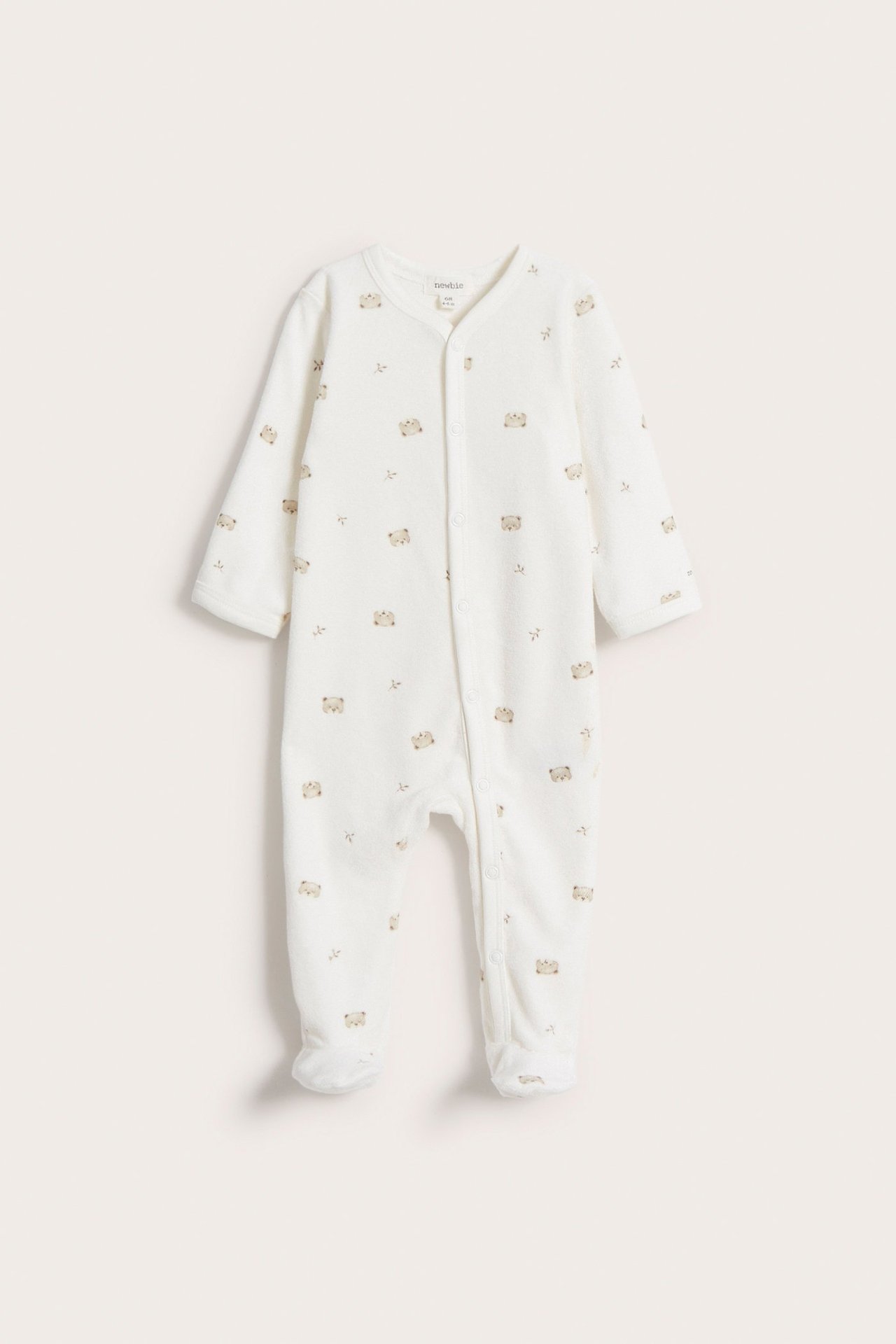 Vorderansicht eines cremefarbenen Baby-Velours-Schlafanzugs mit Teddybärmuster und Druckknöpfen vorne.