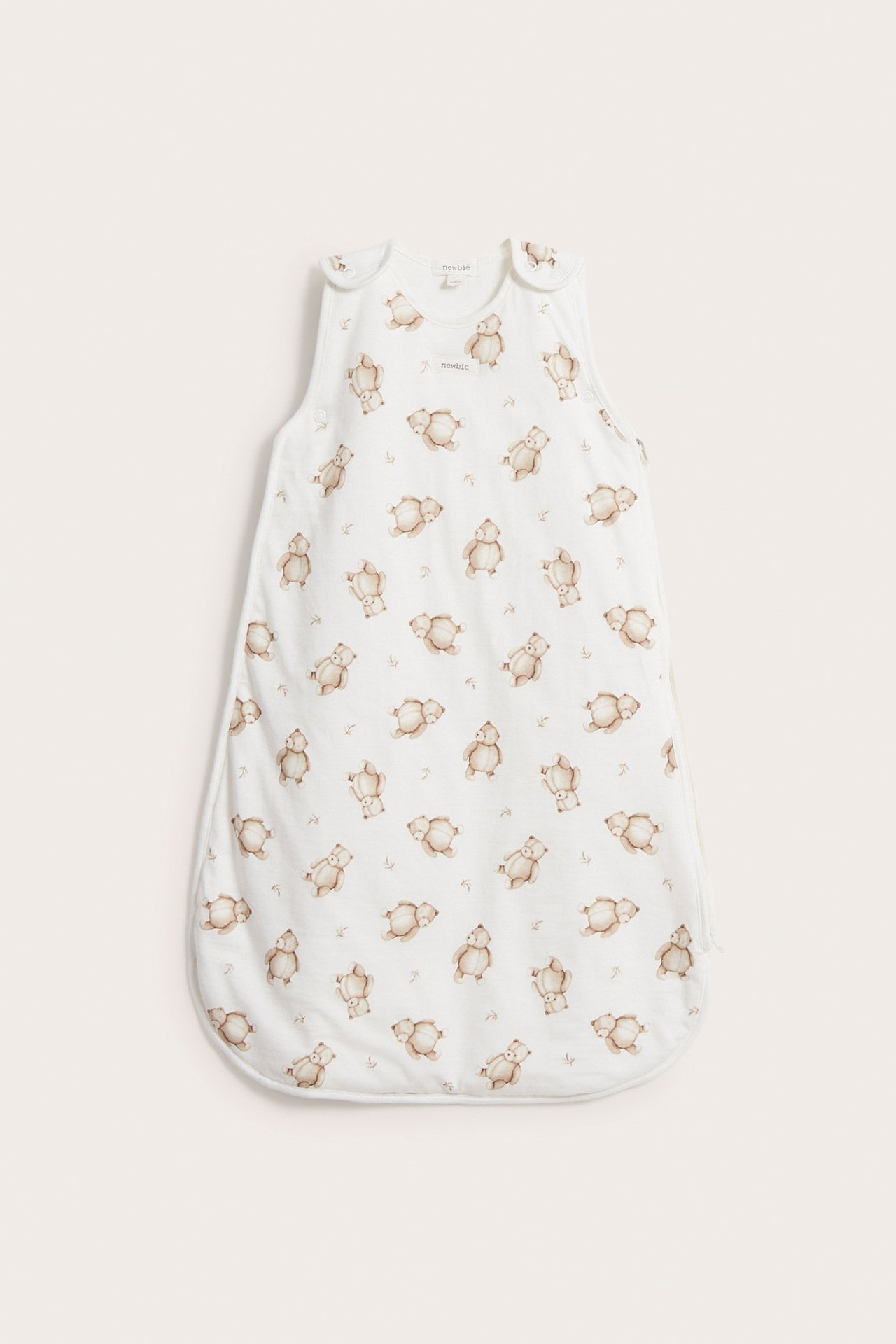 Vorderansicht: Off-weißer Babyschlafsack mit braunem Teddybärenmuster und Schulter-Druckknöpfen.