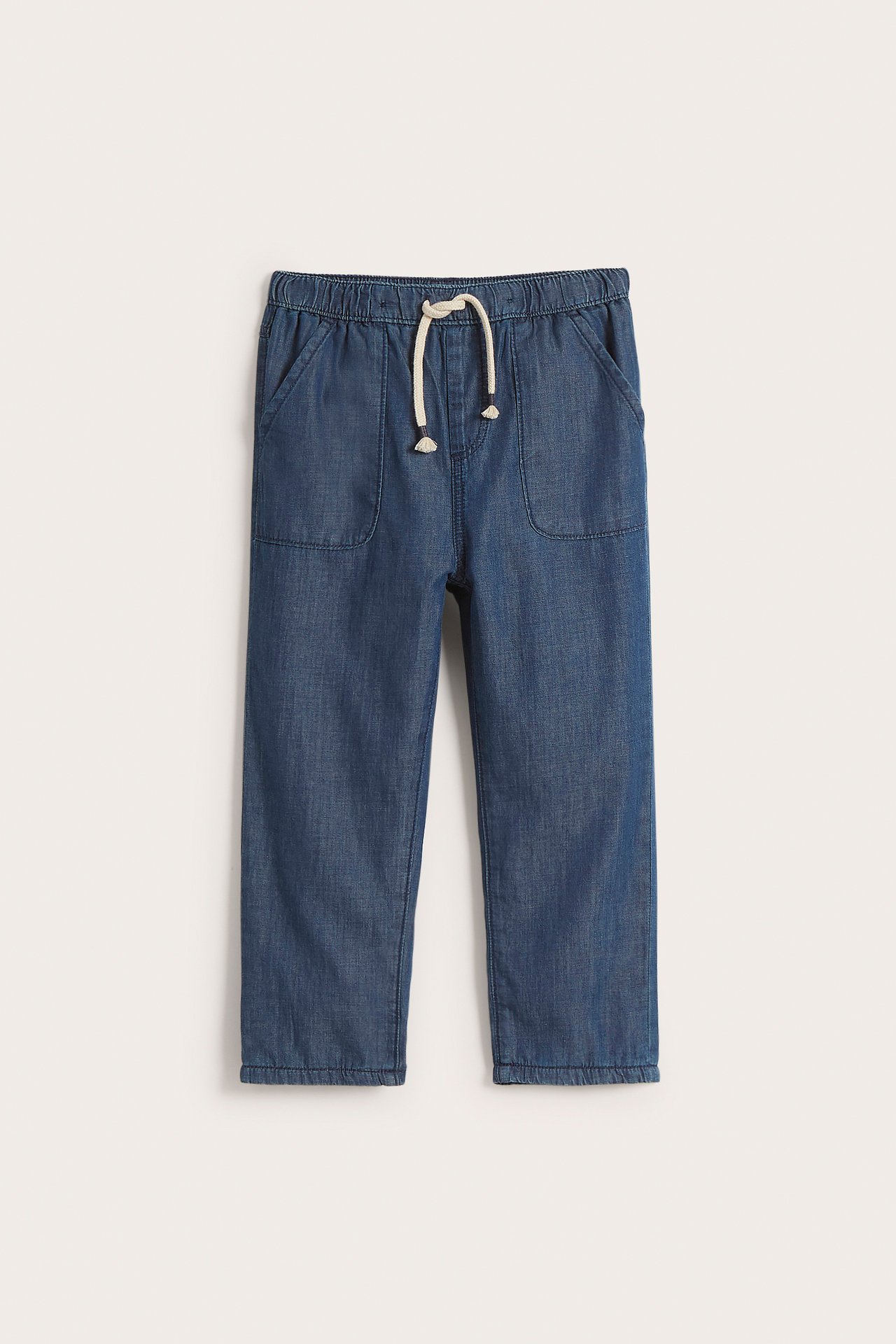 Front view of blue kid's cotton jeans with elasticated waist, white drawstring, and two front pockets.