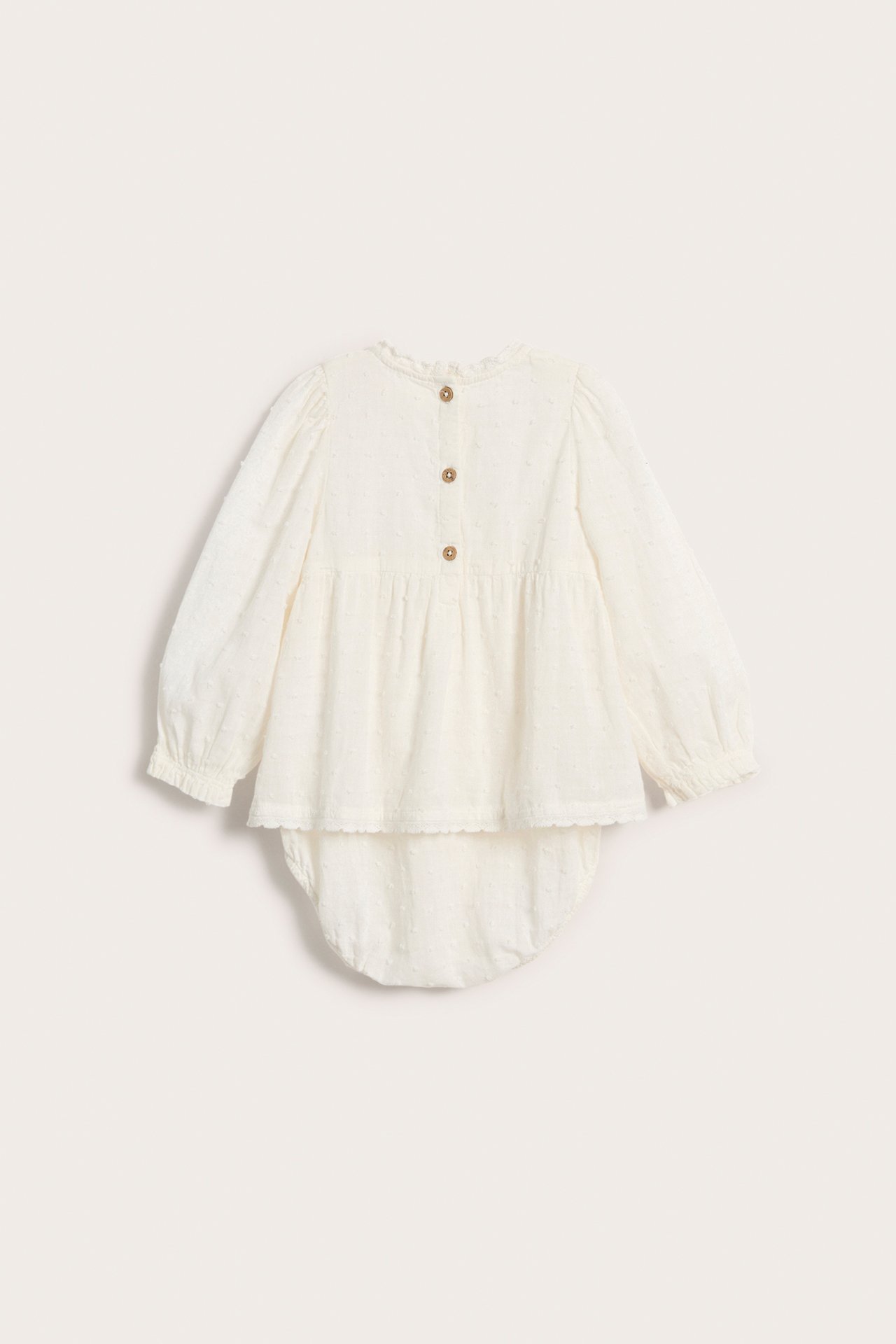 Back view of an off-white baby woven bodysuit with textured dots, long puff sleeves, and button closure.