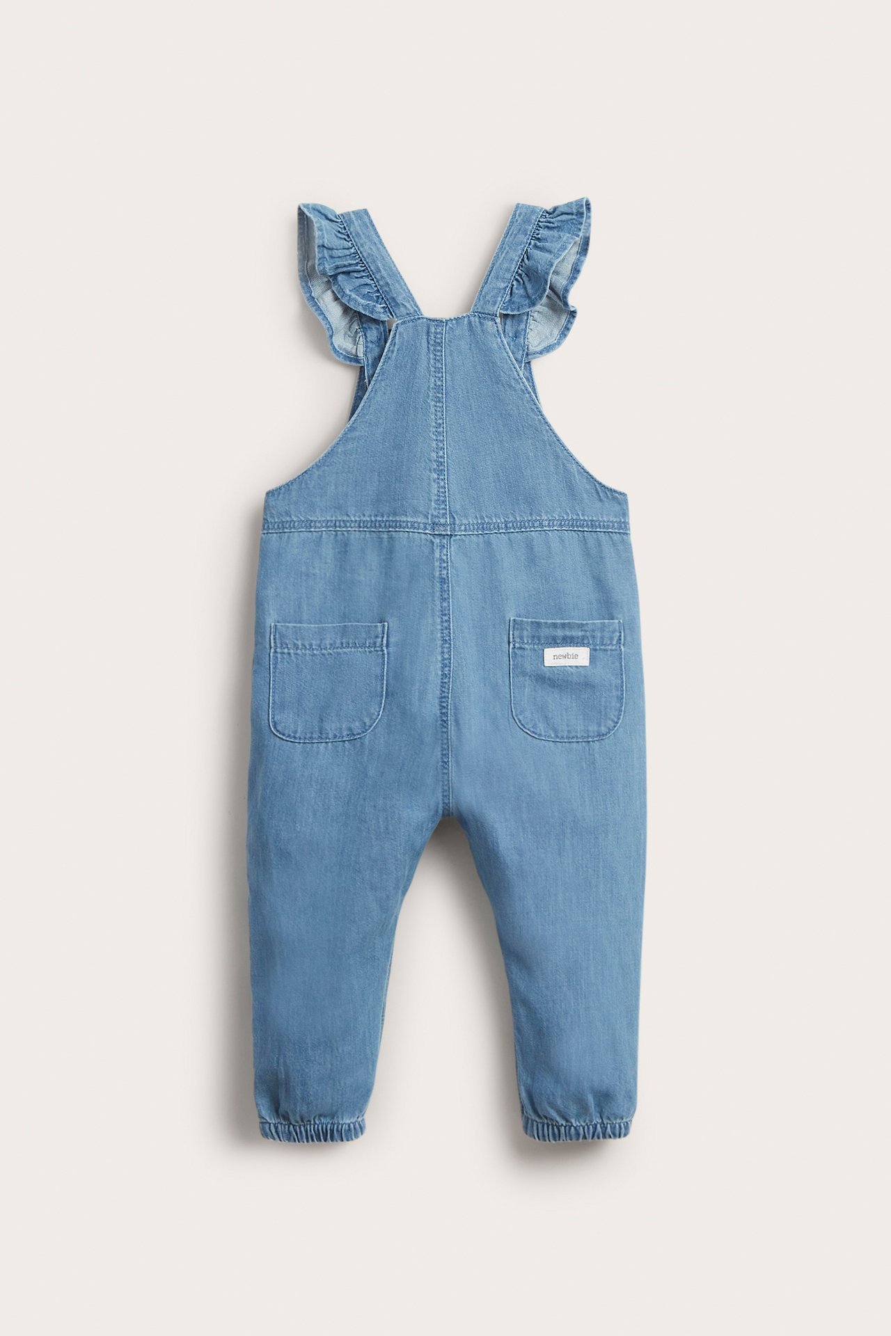 Rückenansicht von hellblauer Baby-Jeanslatzhose mit Rüschenträgern, Gesäßtaschen und elastischen Beinbündchen.