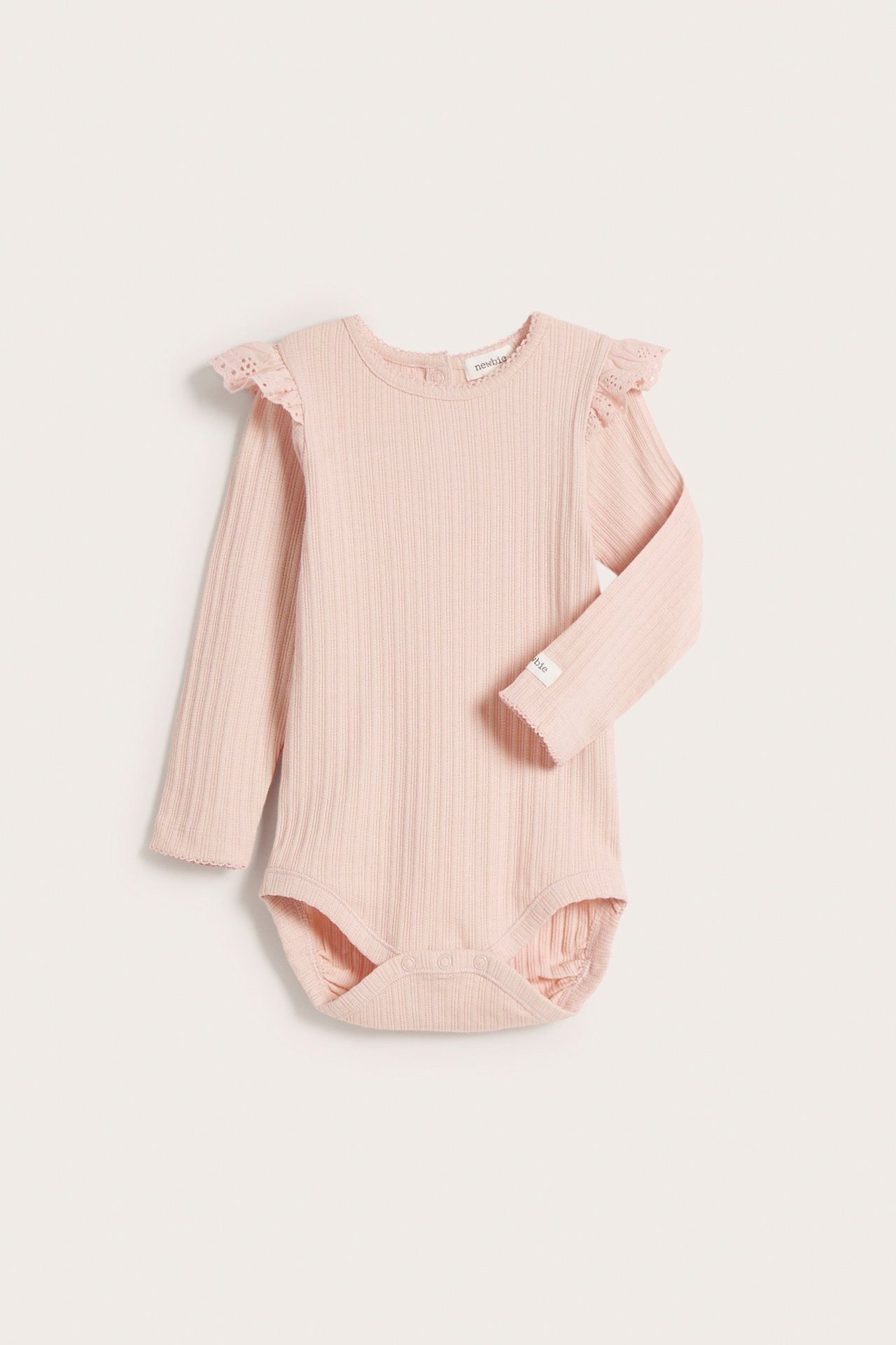 Front view of a light pink ribbed baby bodysuit with long sleeves, shoulder ruffles, and snap buttons.