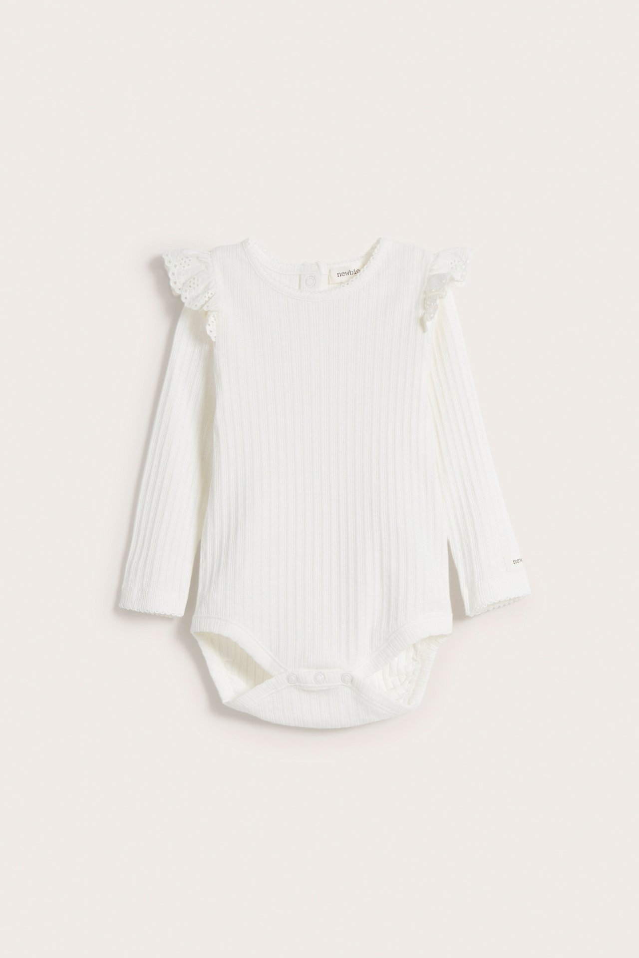 Vorderansicht eines cremeweißen gerippten Baby-Bodys mit langen Ärmeln, Rüschen an den Schultern und Druckknöpfen.