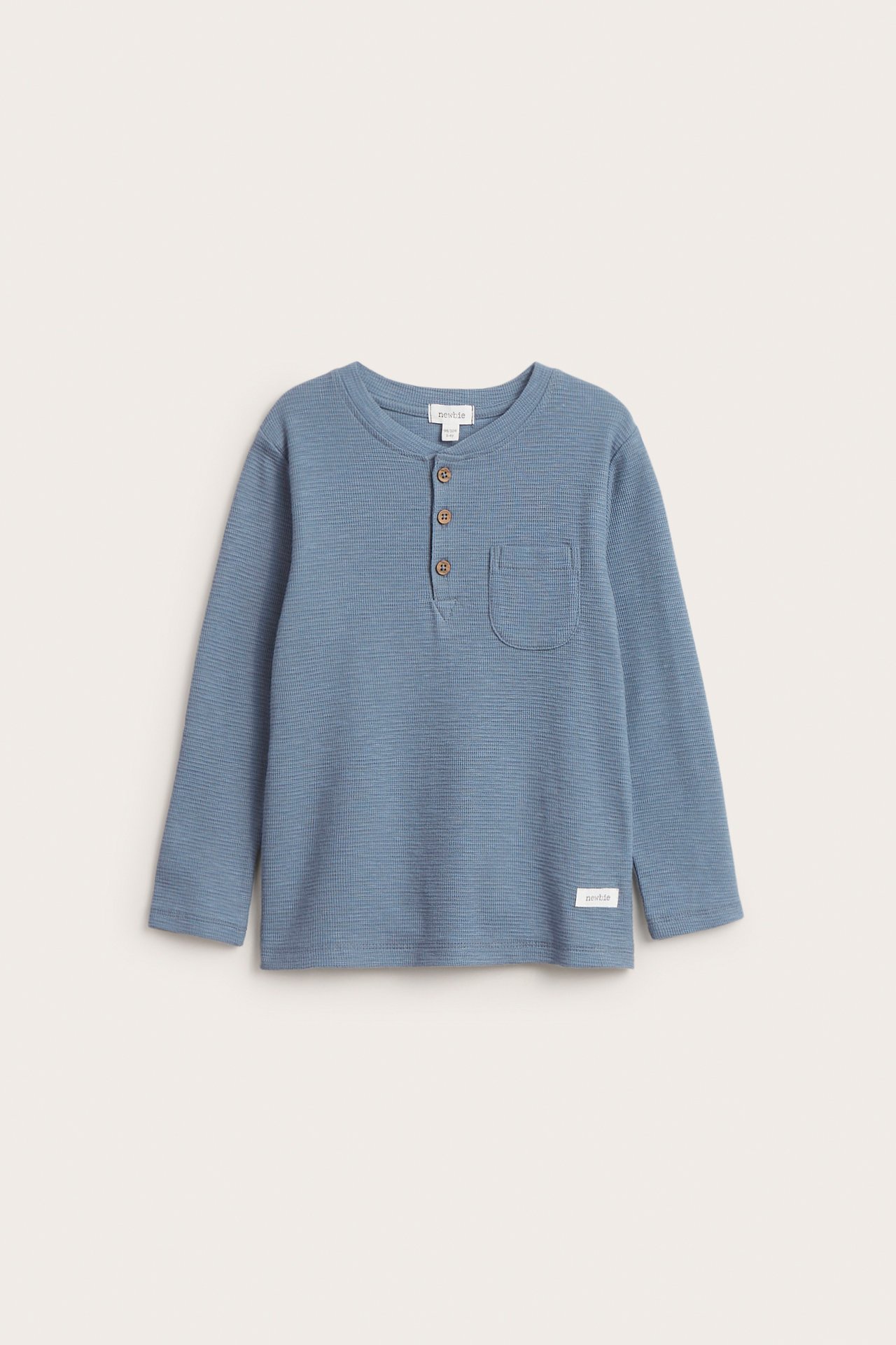 Vorderansicht eines blauen langärmeligen Waffelstrick-Henleyshirts mit drei braunen Knöpfen und Brusttasche.