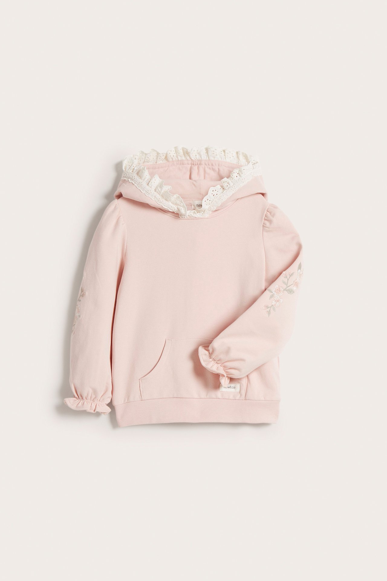 Front view: Kid's light pink cotton hoodie with white lace hood, embroidered sleeves, and kangaroo pocket.