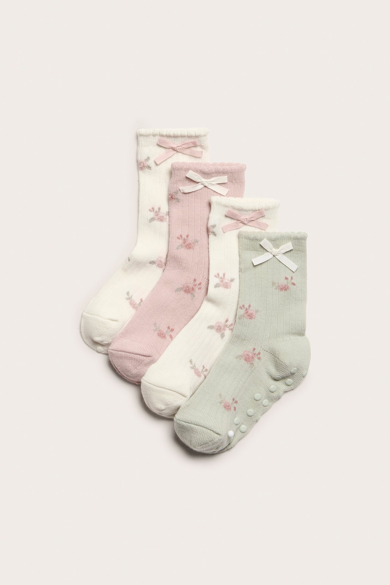 Draufsicht: Vier Paar gestrickte Socken mit Blumenmuster, Schleifen. Verschiedene Farben, eines mit Antirutsch.