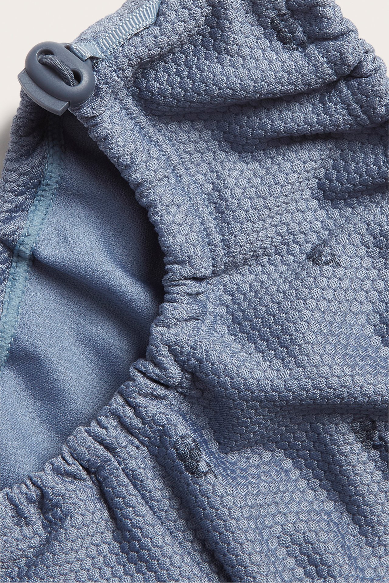 Close-up of blue baby swim shorts with a textured pattern and an adjustable buckle.