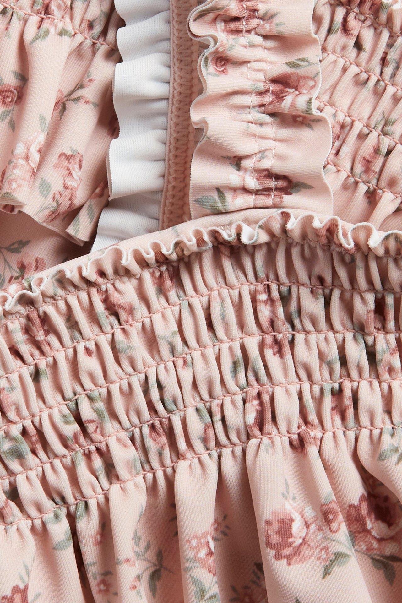 Close-up of a pink floral smocked bikini with white ruffled trim.