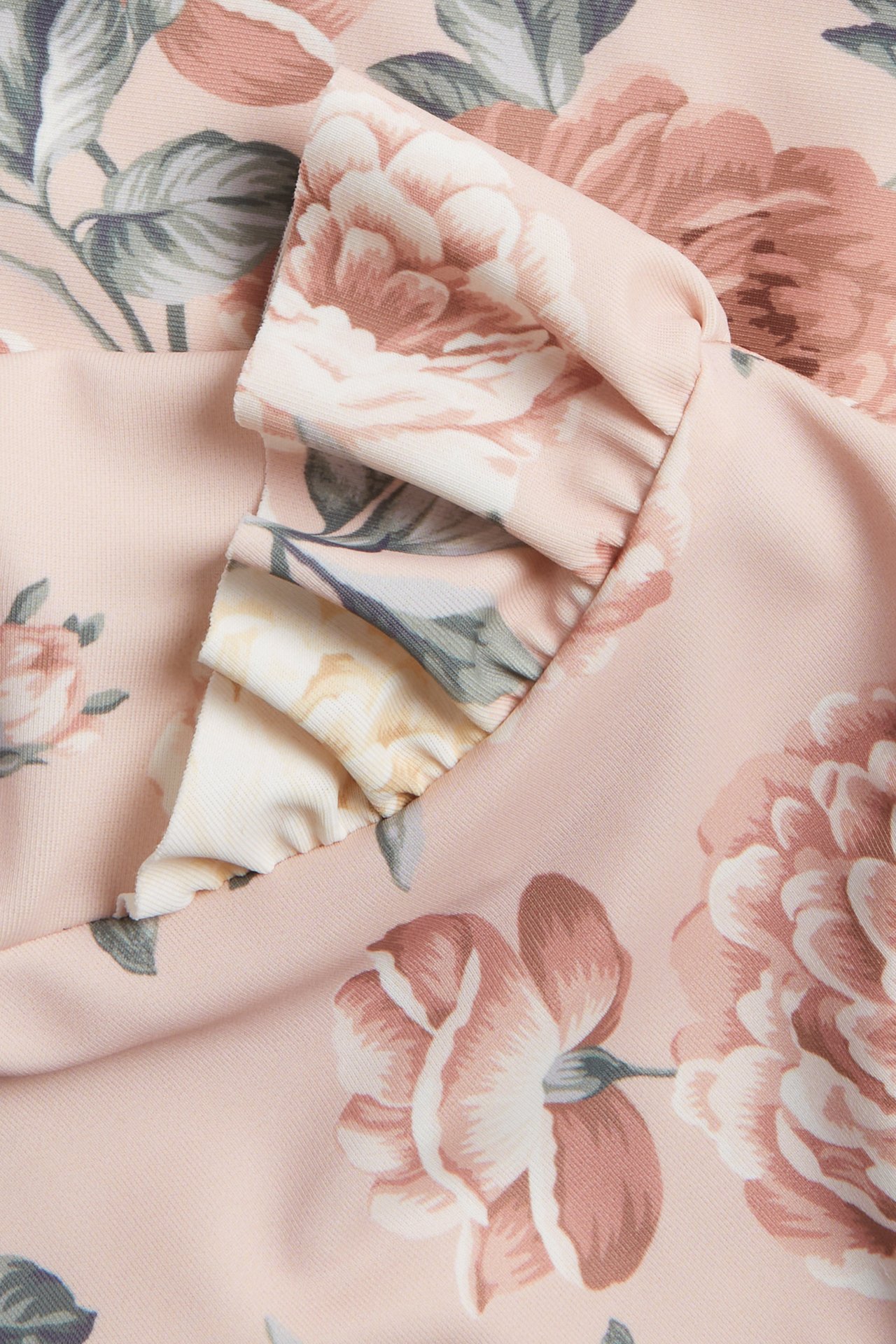 Close-up of a pink floral UV top with decorative ruffles.