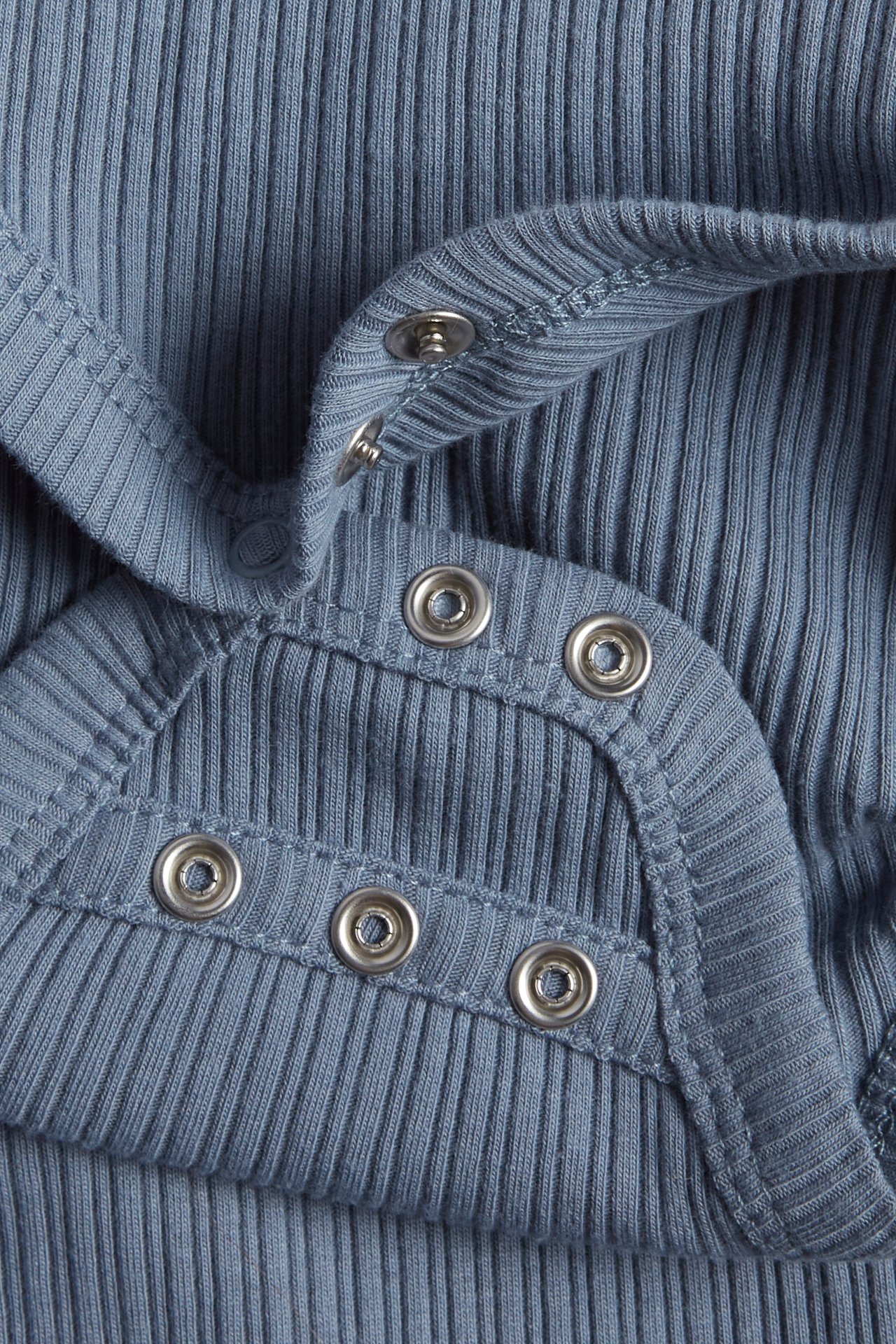 Close-up of a blue ribbed baby wrap-around bodysuit with silver snap buttons.