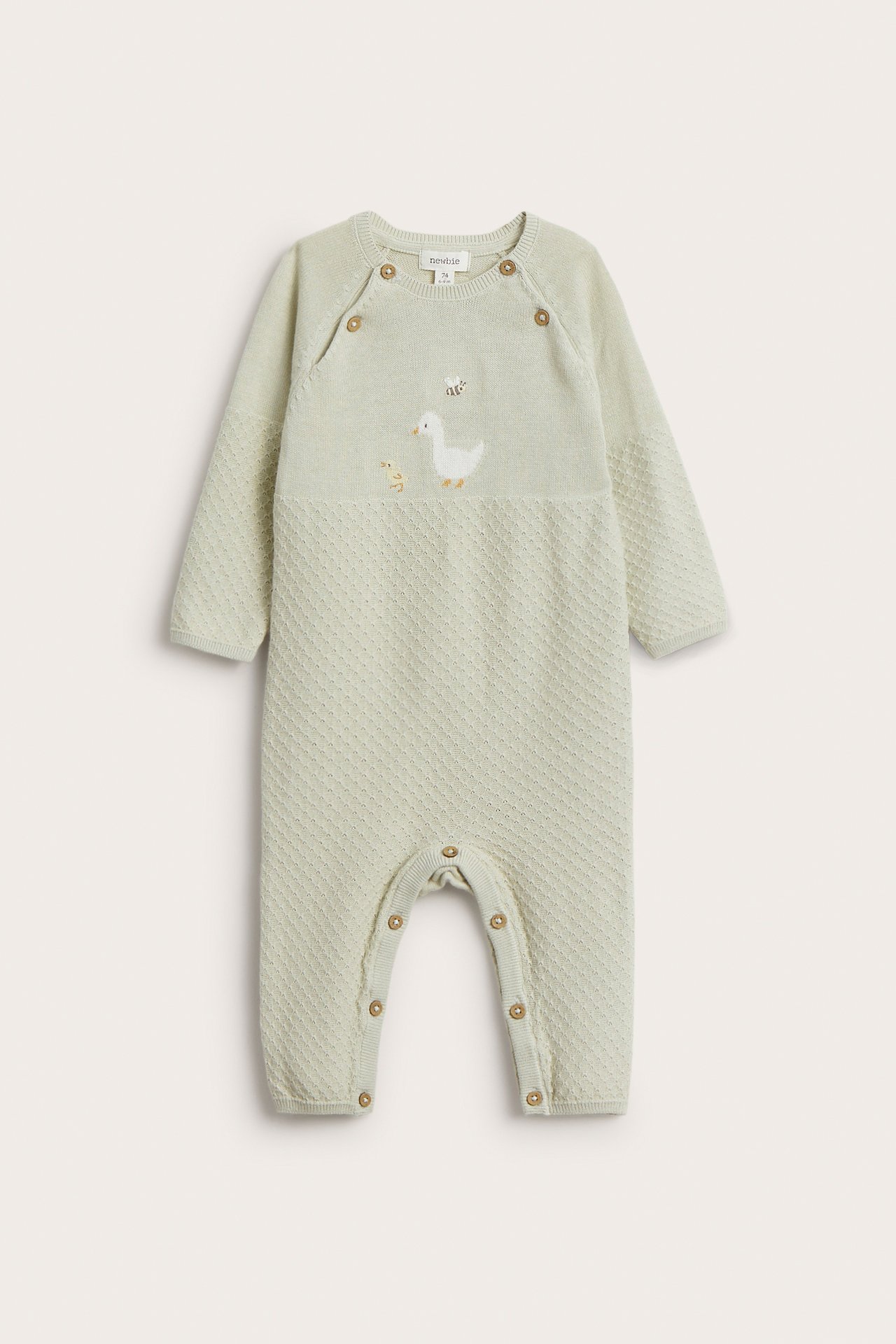 Front view of a baby's light green knitted cotton coverall with duck embroidery, shoulder buttons, and crotch snaps.