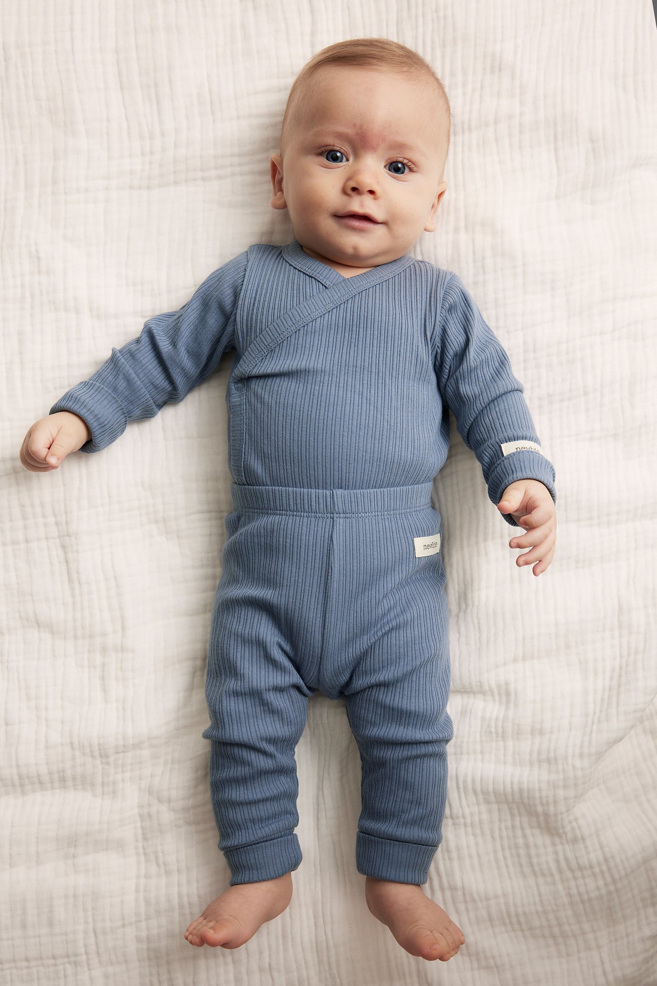 Top-down view of a baby wearing blue ribbed leggings with an elastic waist and a matching wrap top.