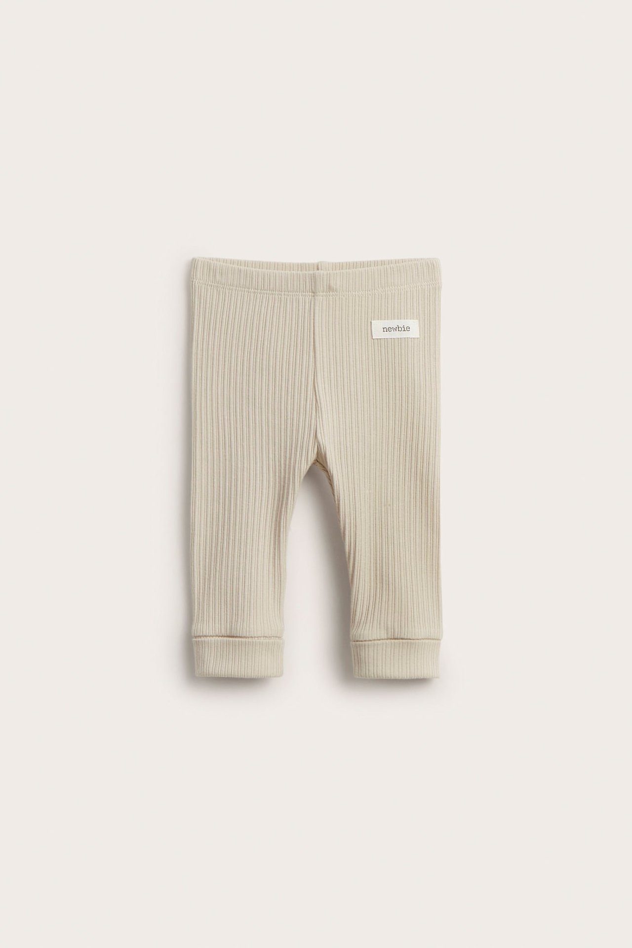 Vorderansicht beiger gerippter Baby-Leggings mit Gummizugbund und umgeschlagenen Bündchen.