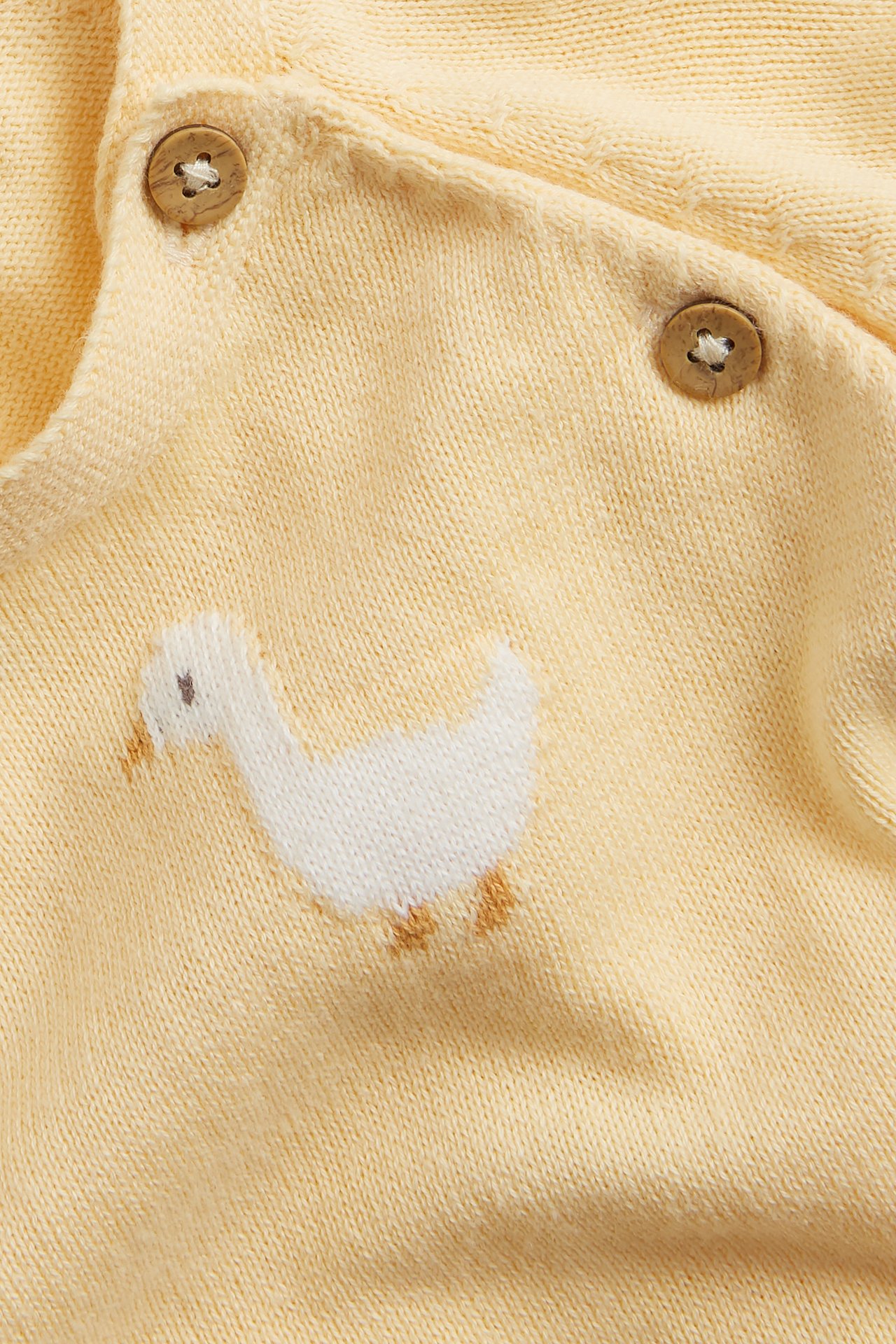 Close-up of a yellow knitted cotton cardigan with white duck embroidery and brown side buttons.