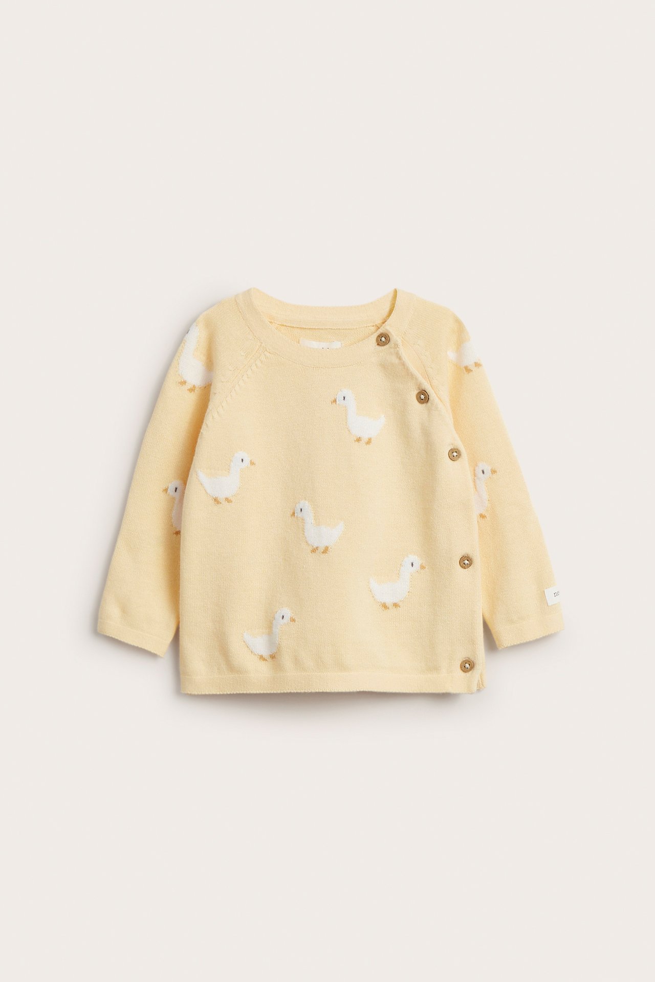Front view of a baby's yellow knitted cotton cardigan with white duck pattern and side wooden button fastening.