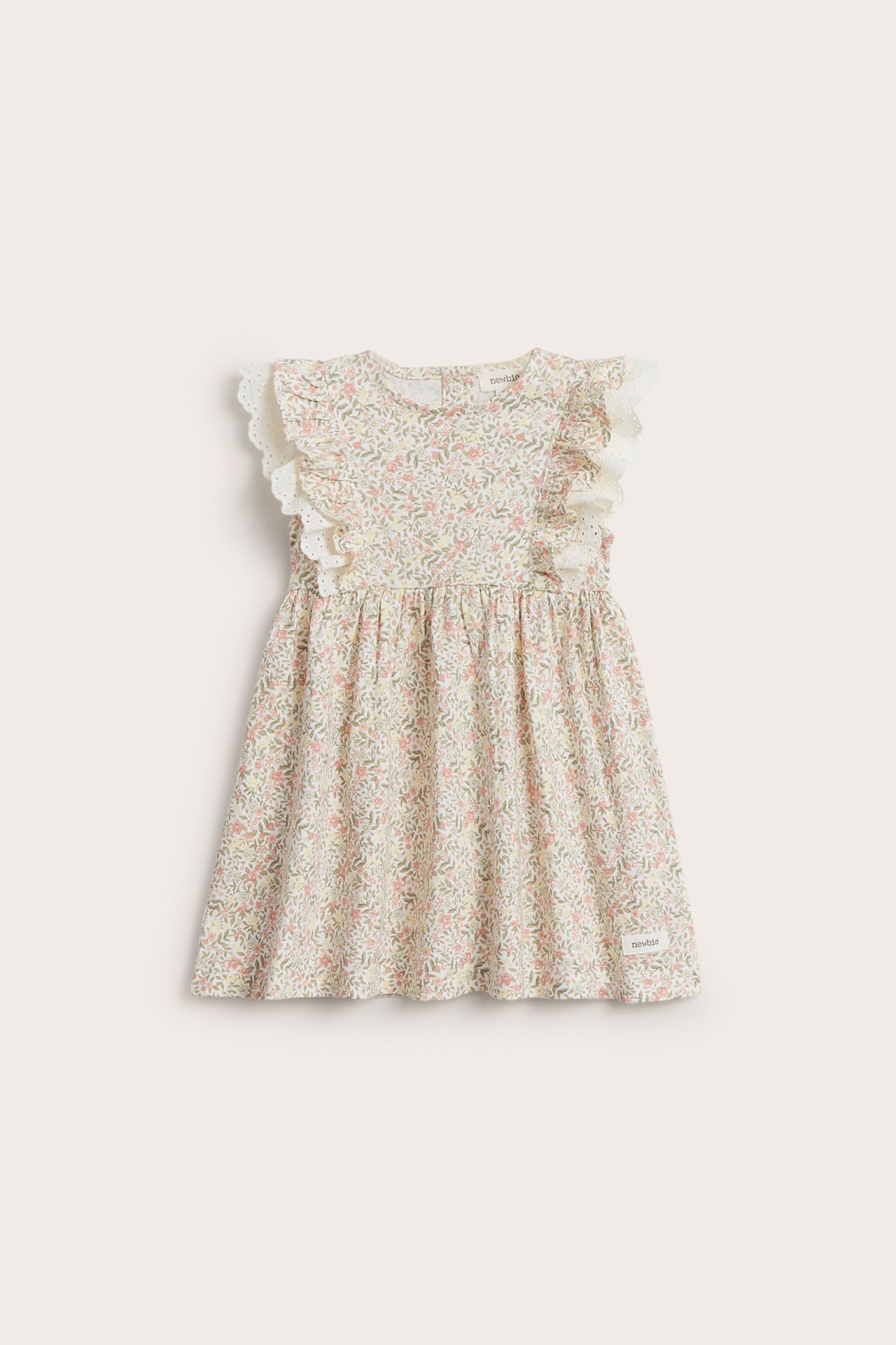 Vorderansicht eines cremefarbenen ärmellosen Babykleides aus Baumwolle mit Blumenmuster und Rüschenspitze.