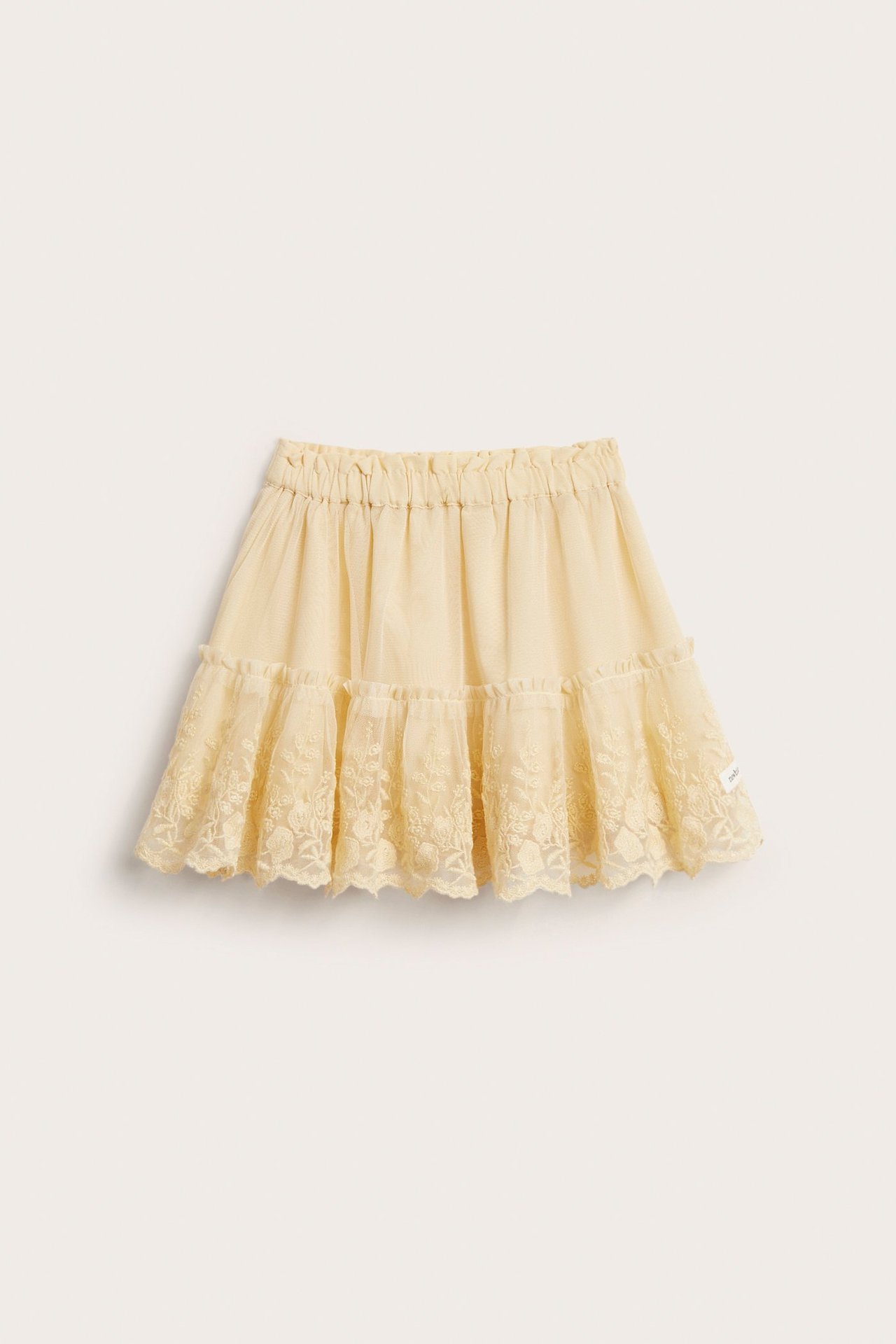 Front view of a kid's light yellow mesh skirt with an elasticated waist and embroidered floral ruffles.