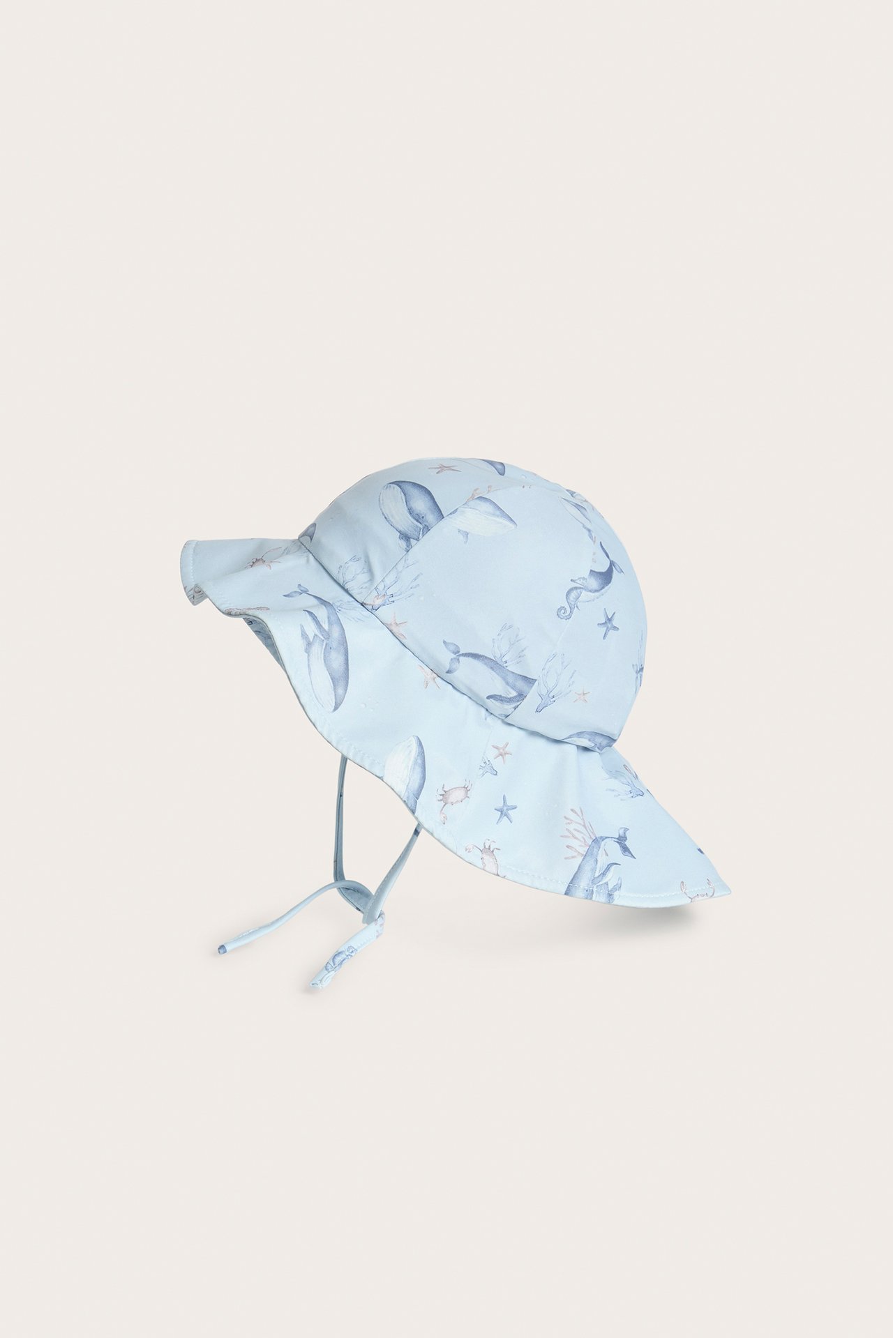 Seitenansicht eines hellblauen Baby-Sonnenhuts mit Wal- und Meerestier-Muster und Bindebändern.
