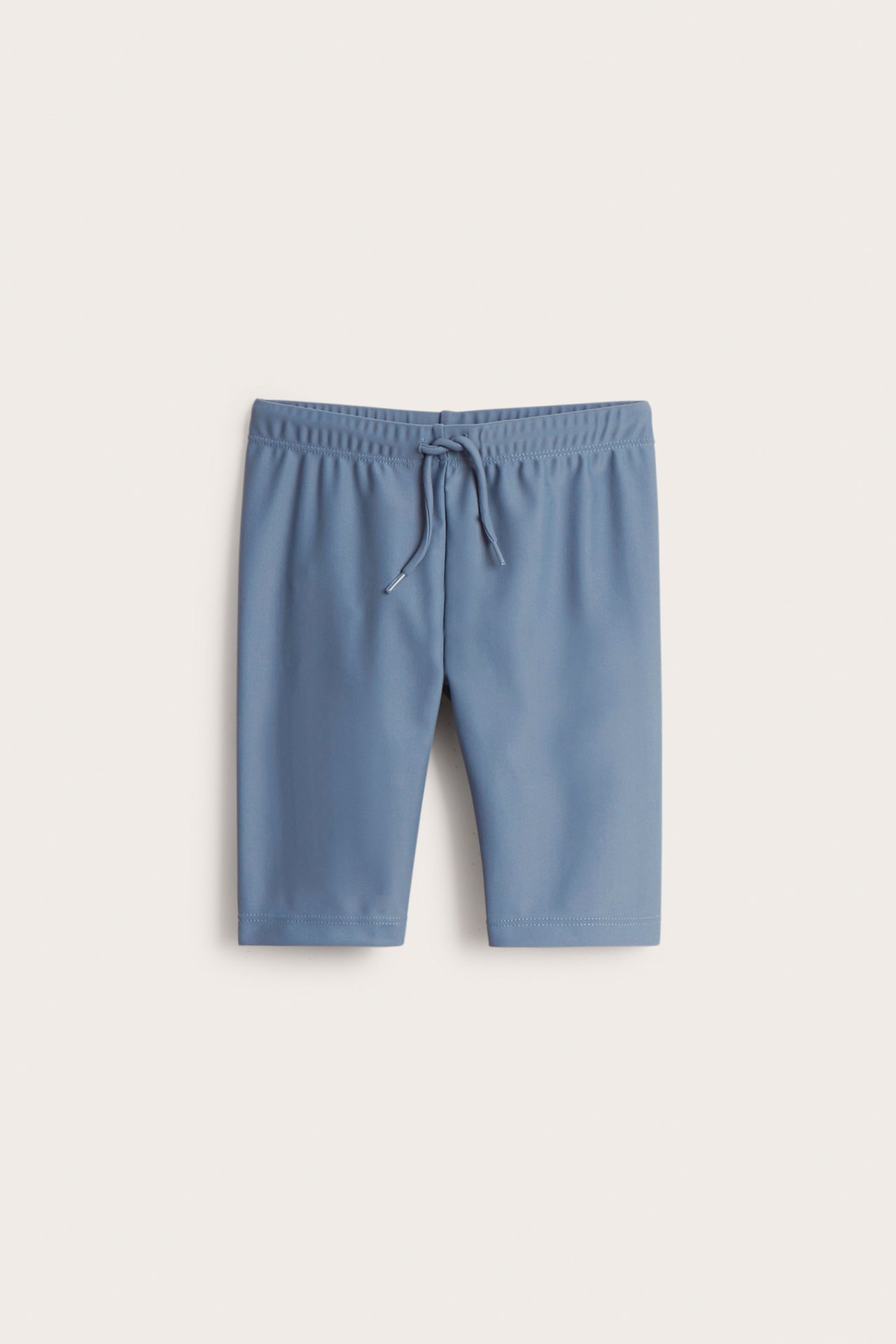 Front view of plain blue three-quarter length UV swim shorts with a drawstring waist.